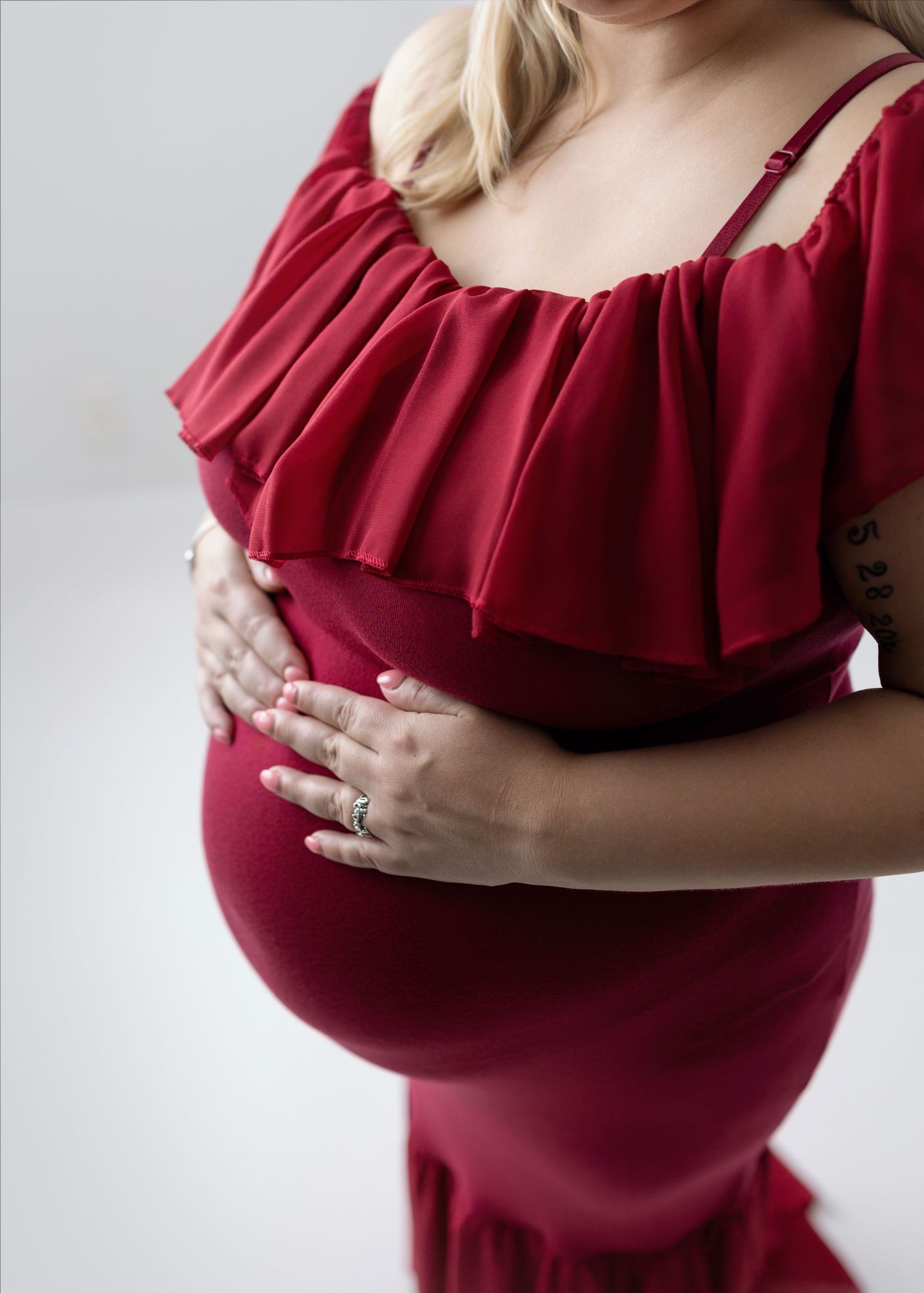 Close-up details of burgundy ruffle neckline on maternity dress.