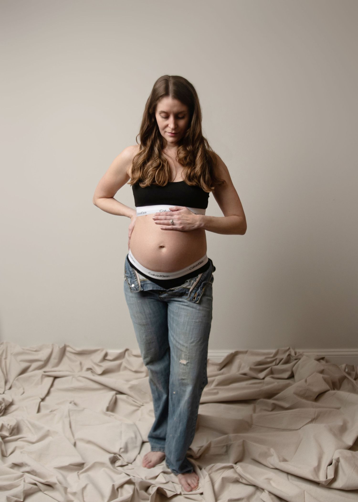 Documentary style maternity photos showing casual moments in denim and black top.