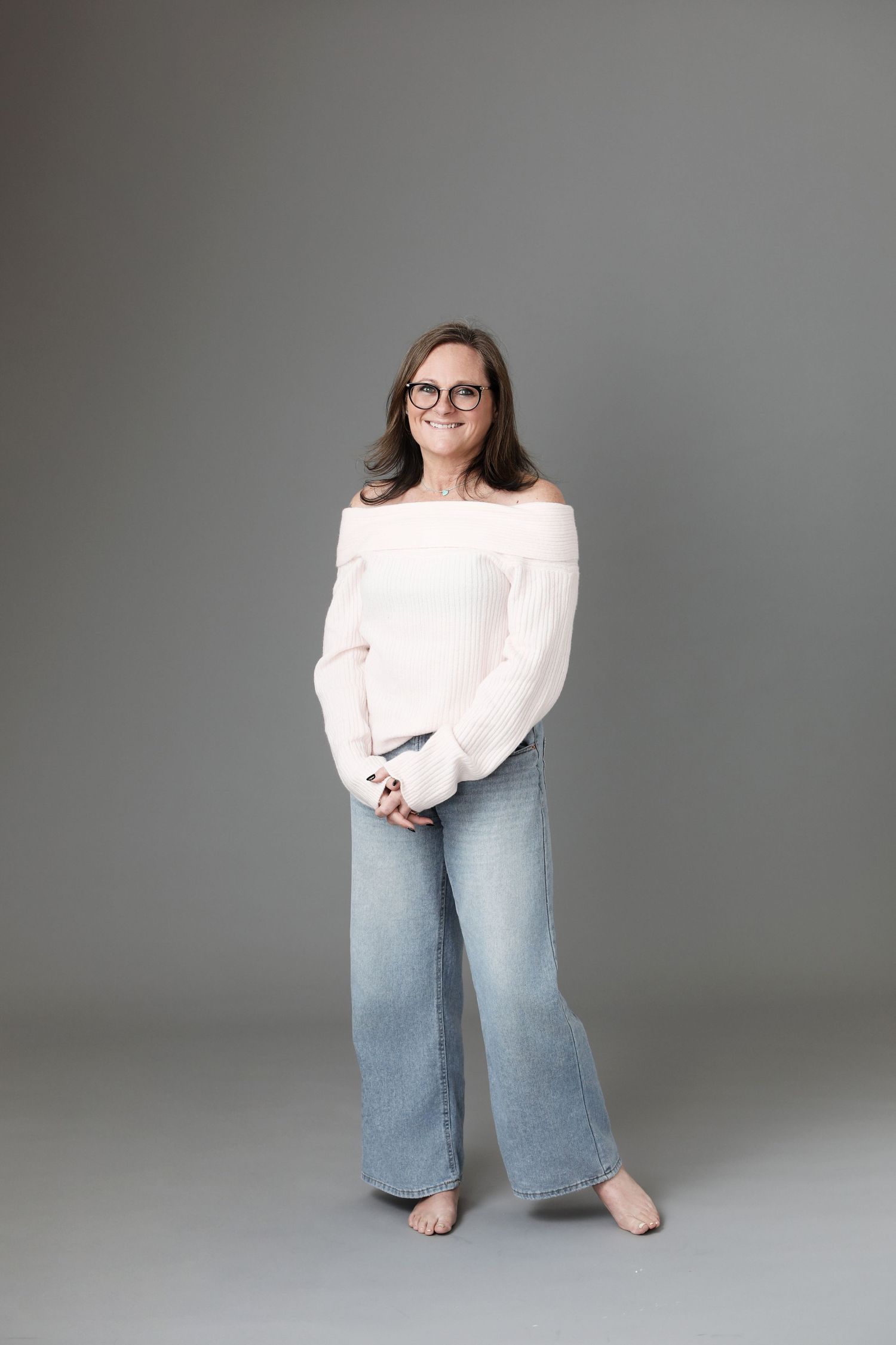 Person wearing white top and light blue wide-leg jeans poses in various positions against gray studio backdrop.
