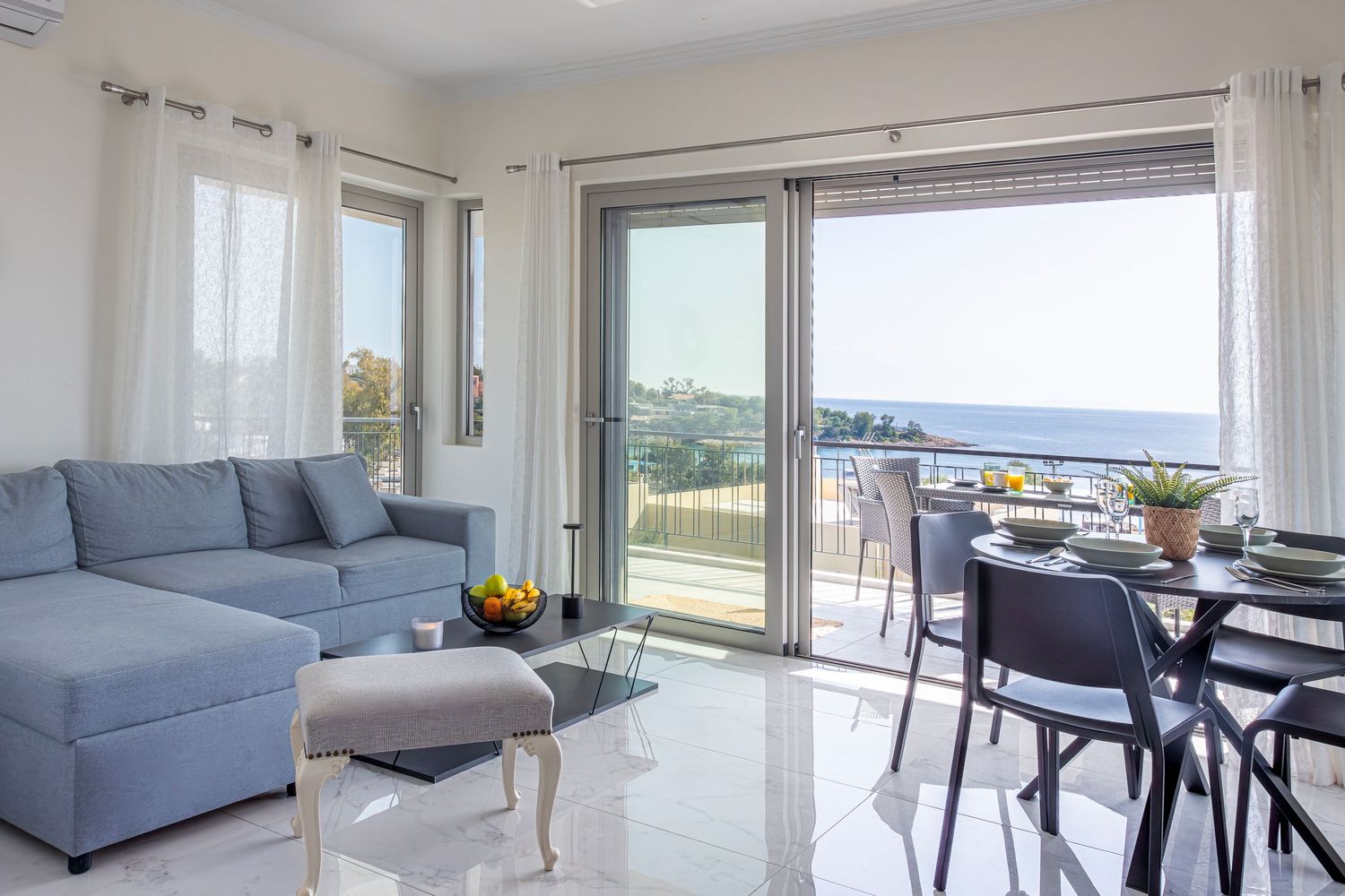 Elegant coastal apartment interior featuring gray sectional and panoramic ocean views.