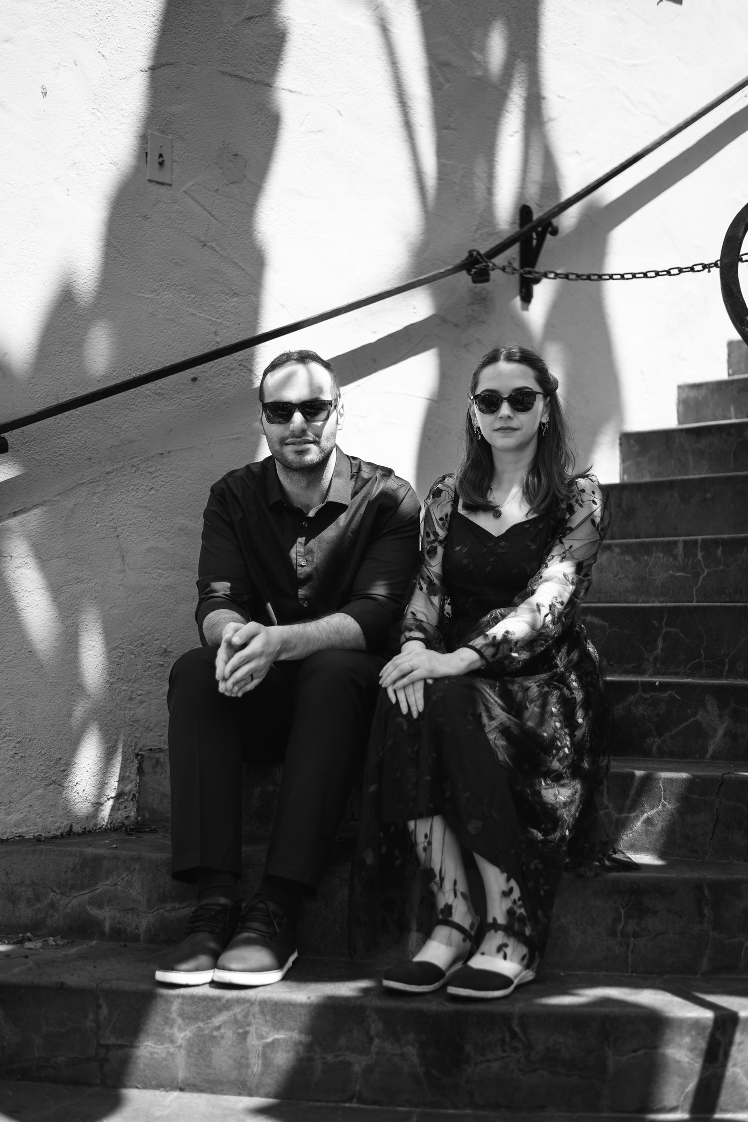 Natural editorial documentary Santa Barbara courthouse wedding moment of a couple sitting on sunlit steps in black and white.