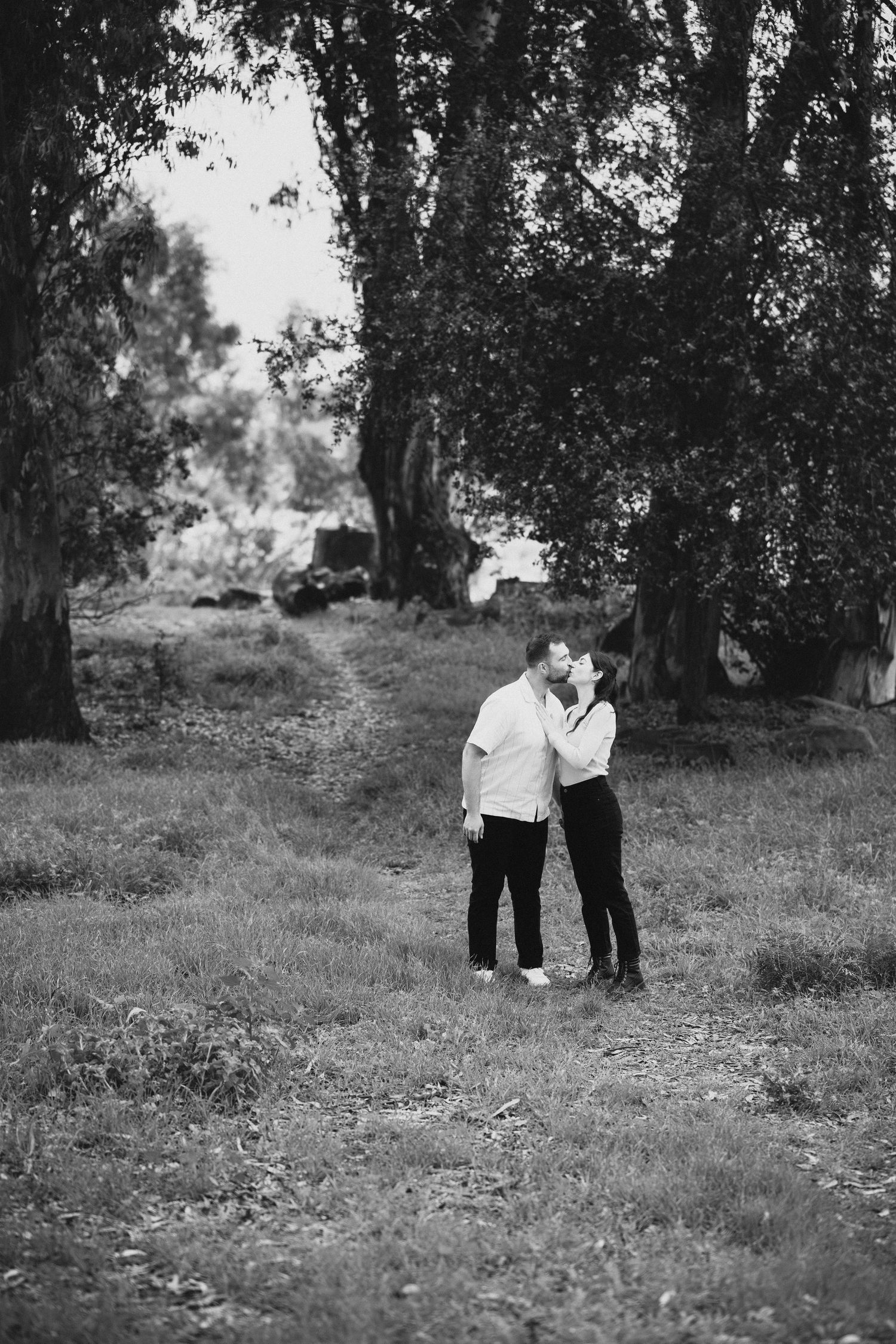 Black and white engaged couple kissing among eucalyptus trees Franceschi Park Santa Barbara documentary engagement photographer Herics Photo