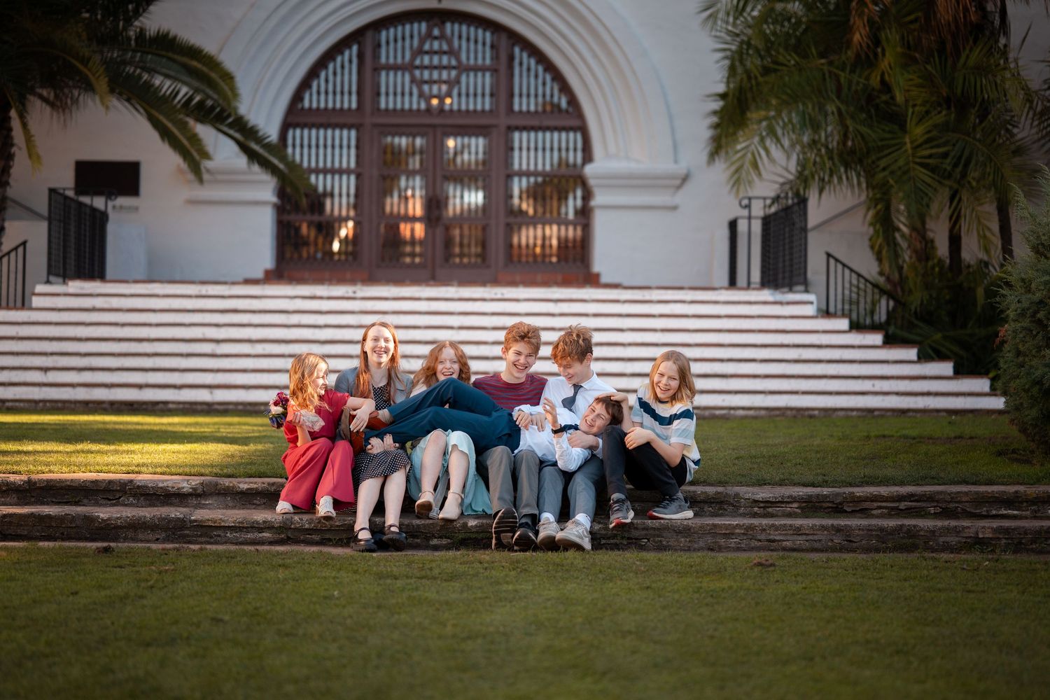 Natural editorial documentary Santa Barbara courthouse wedding moment of a group kids sitting on front steps beneath the arched entrance.