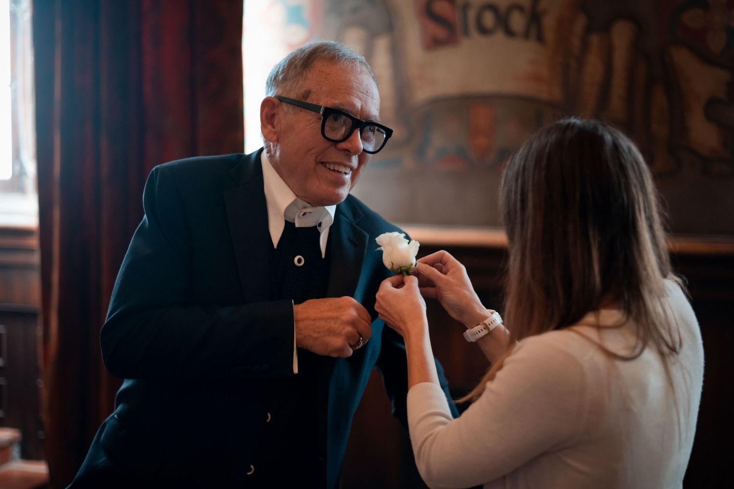 Natural editorial documentary Santa Barbara courthouse wedding moment of a boutonniere being pinned to a suit in soft indoor light.