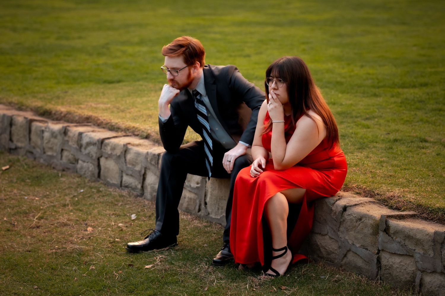 Natural editorial documentary elopement moment of a couple sitting together on a stone wall, sharing a quiet pause in warm evening light.