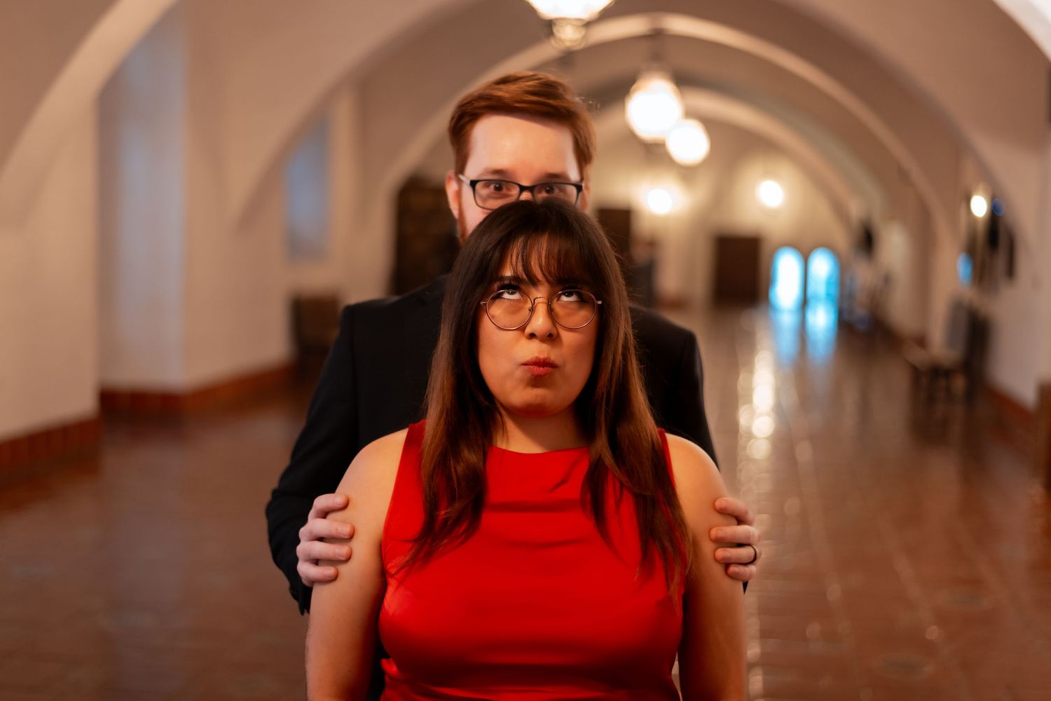 Natural editorial documentary elopement moment of a couple standing in an arched hallway, sharing a quiet touch in warm indoor light.