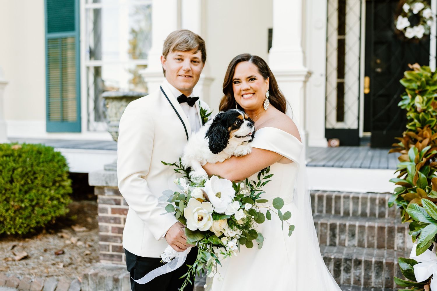 A bride and groom share romantic moments during their wedding photoshoot at an elegant venue with white floral bouquets.