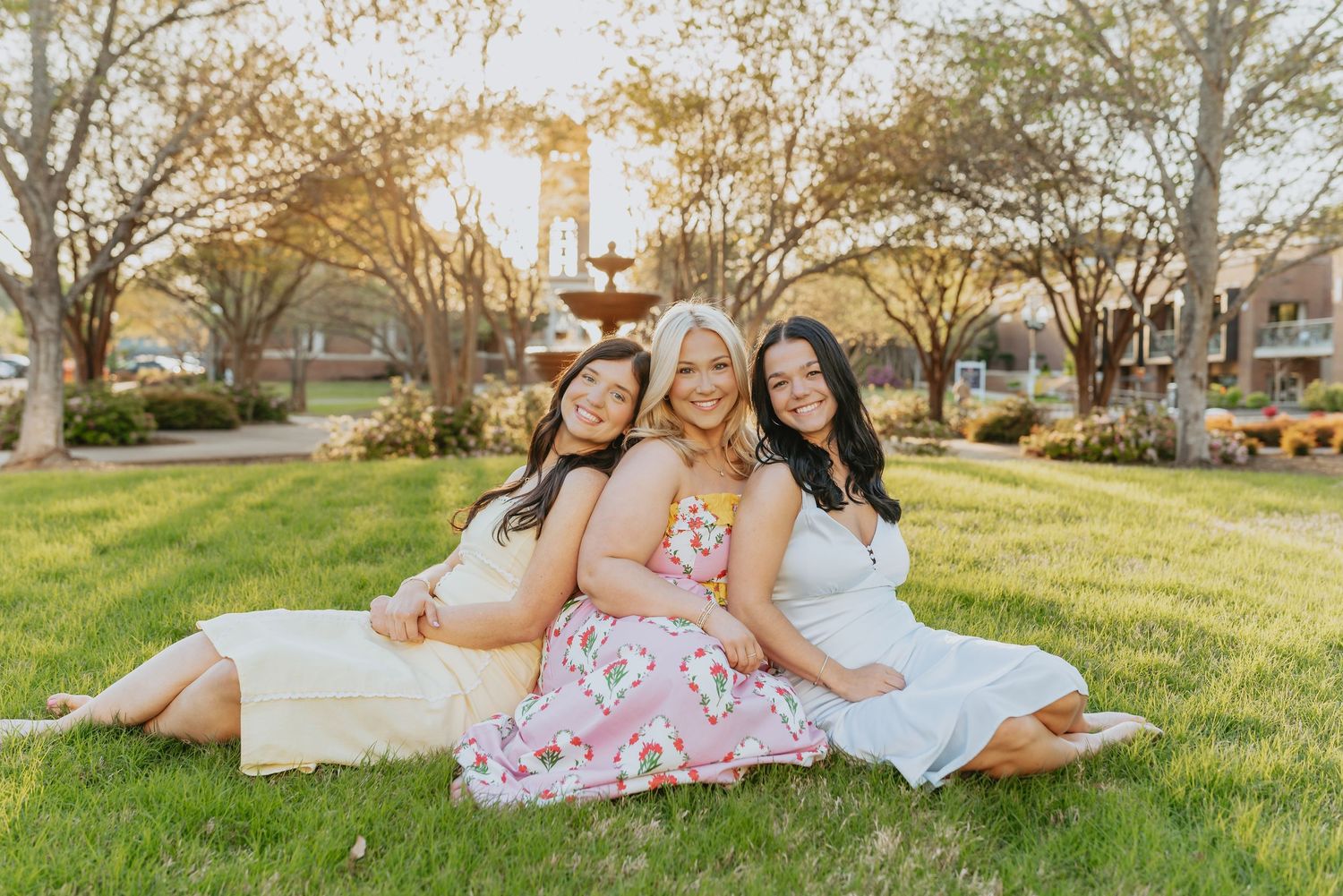 Family members lounging together on a grassy lawn during a casual outdoor photo session.
