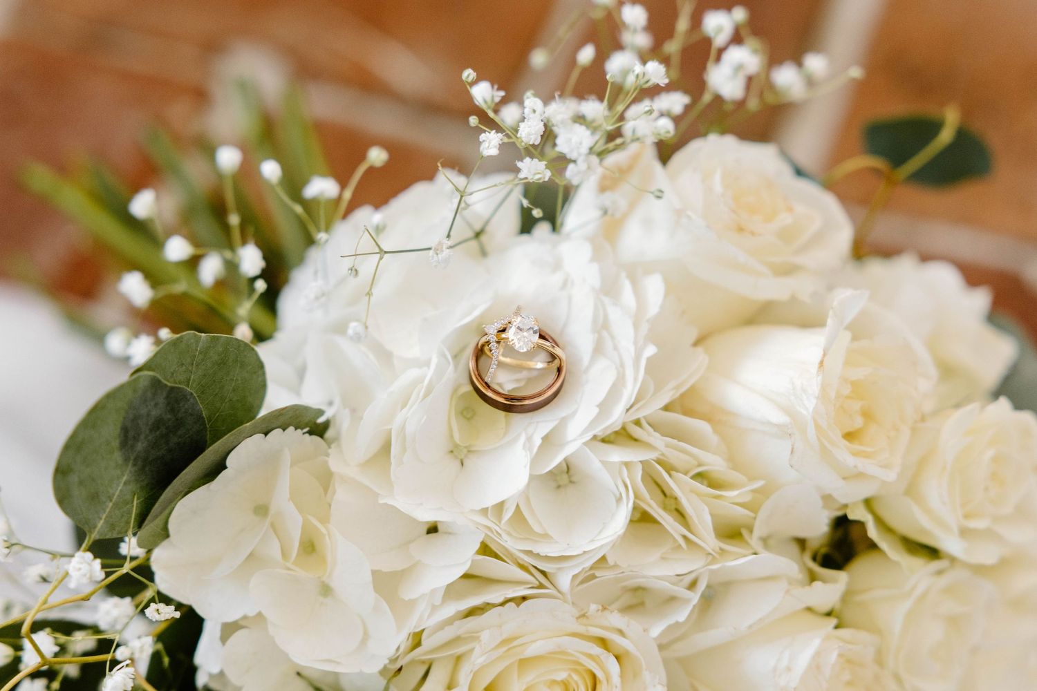 White roses and wedding rings arranged on a light surface with delicate details.