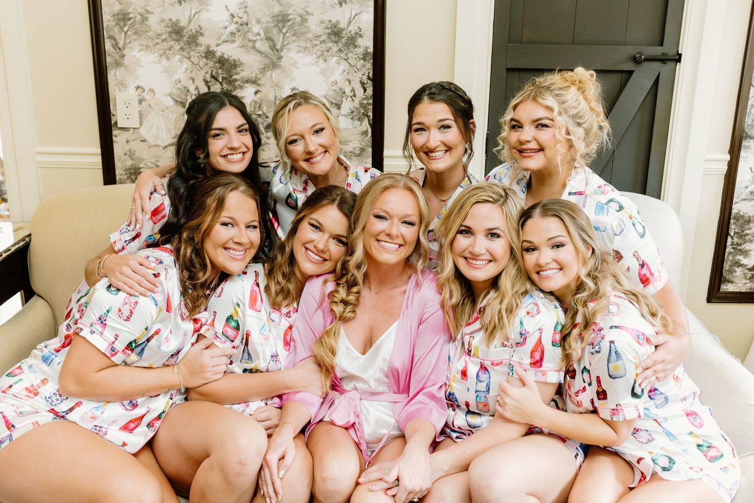 Bridal party wearing matching floral robes poses together during wedding day preparations.