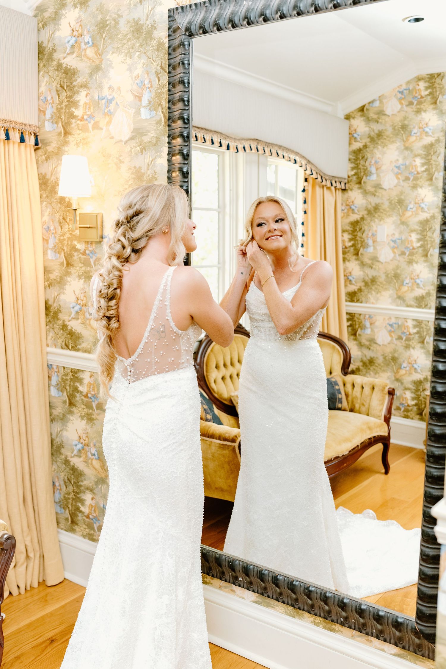Getting ready moments captured in an elegant room with ornate mirrors and wallpaper.