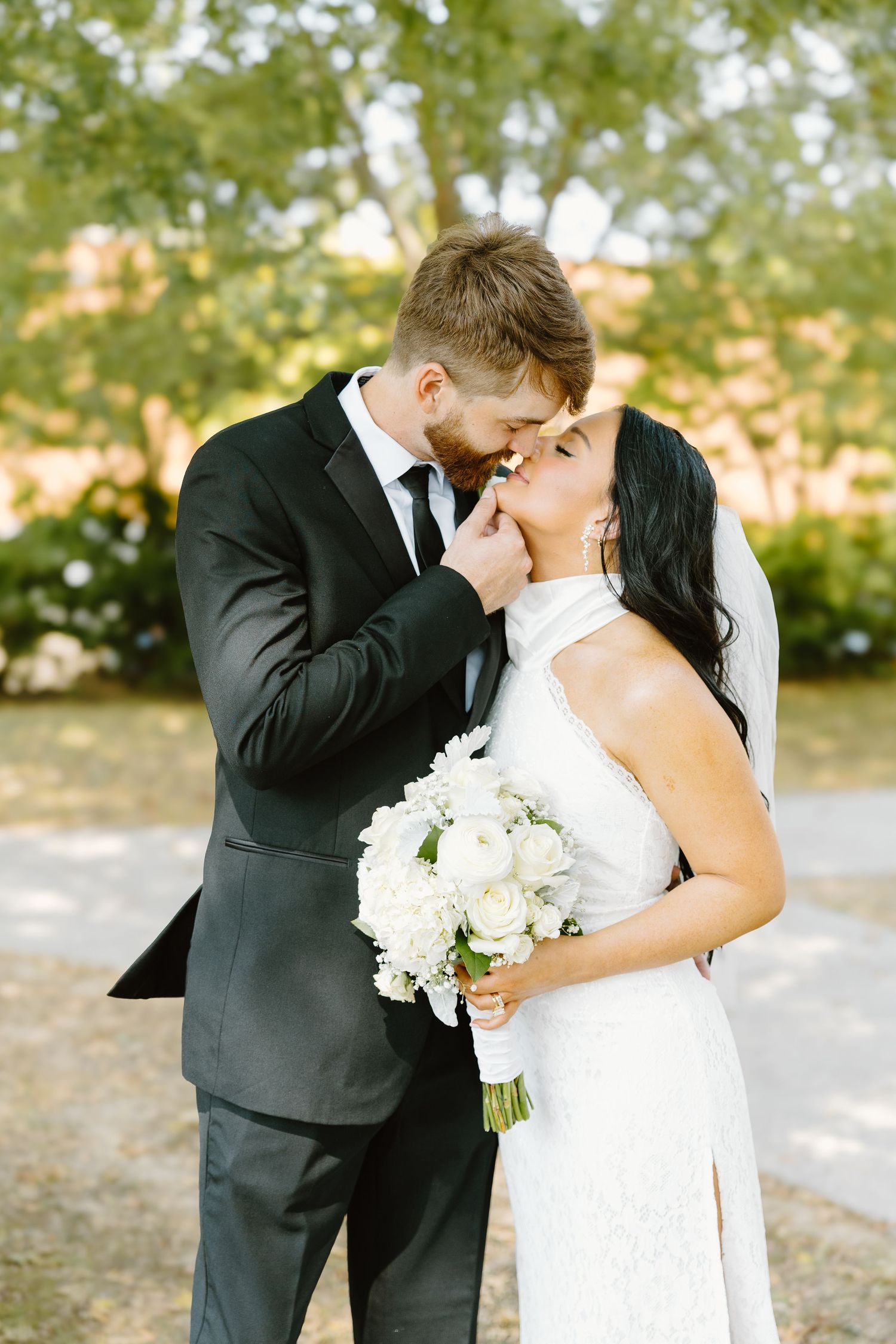 Romantic wedding couple shares intimate kisses in a series of outdoor portrait photos with white bouquet.