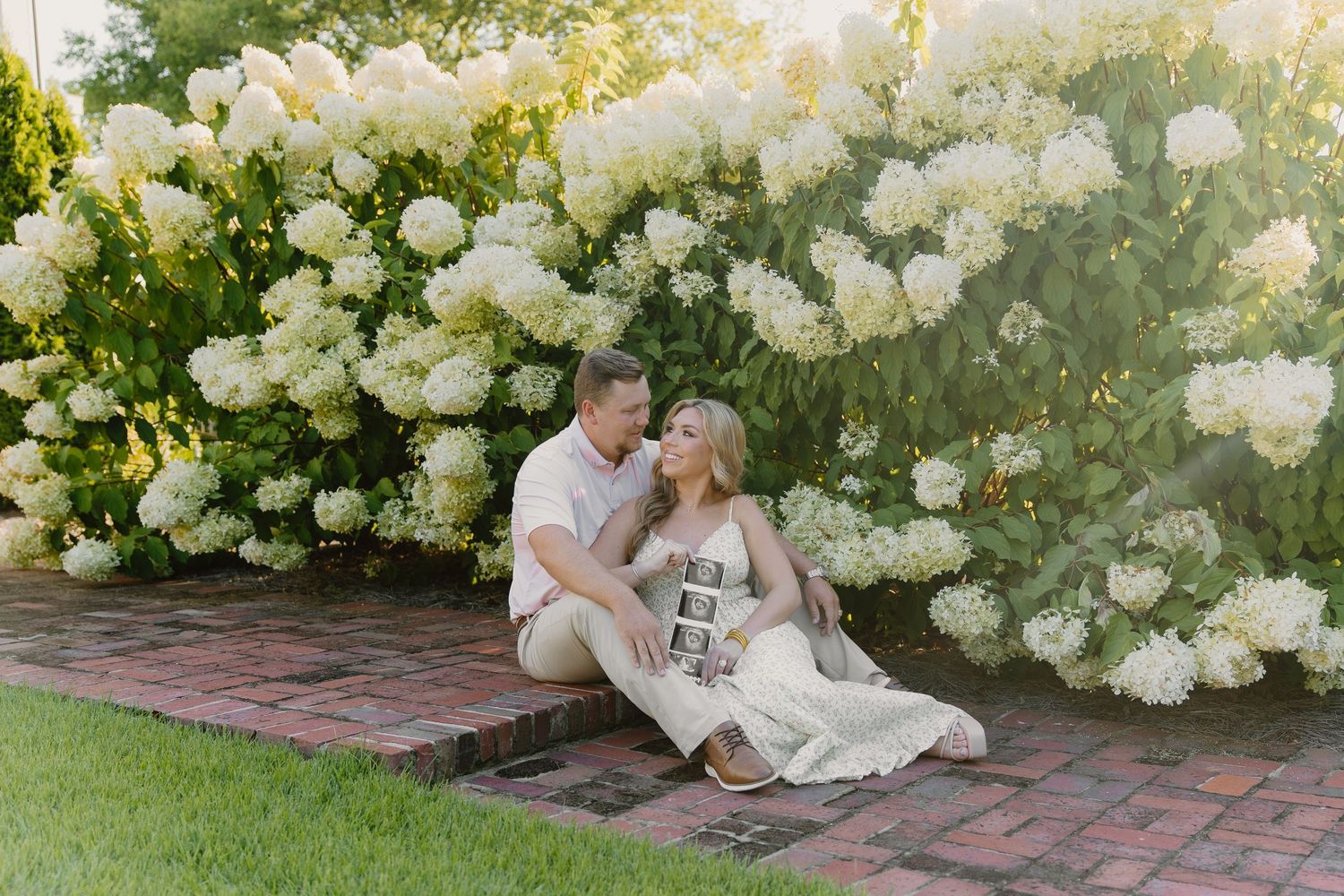 Romantic scene against a backdrop of blooming white hydrangea bushes in a garden setting.