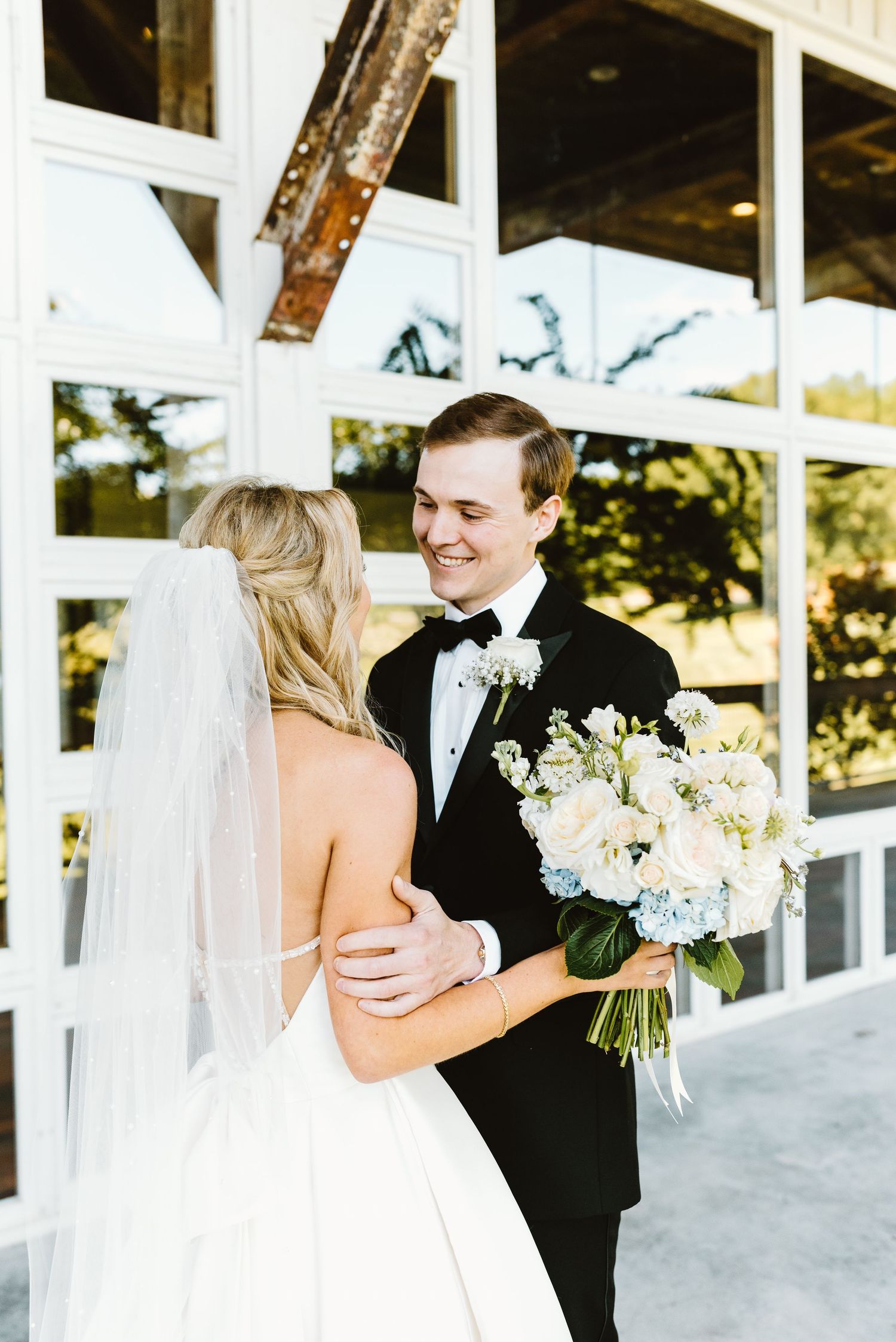 A happy couple shares a joyful moment together during their wedding ceremony outdoors in front of white columns.