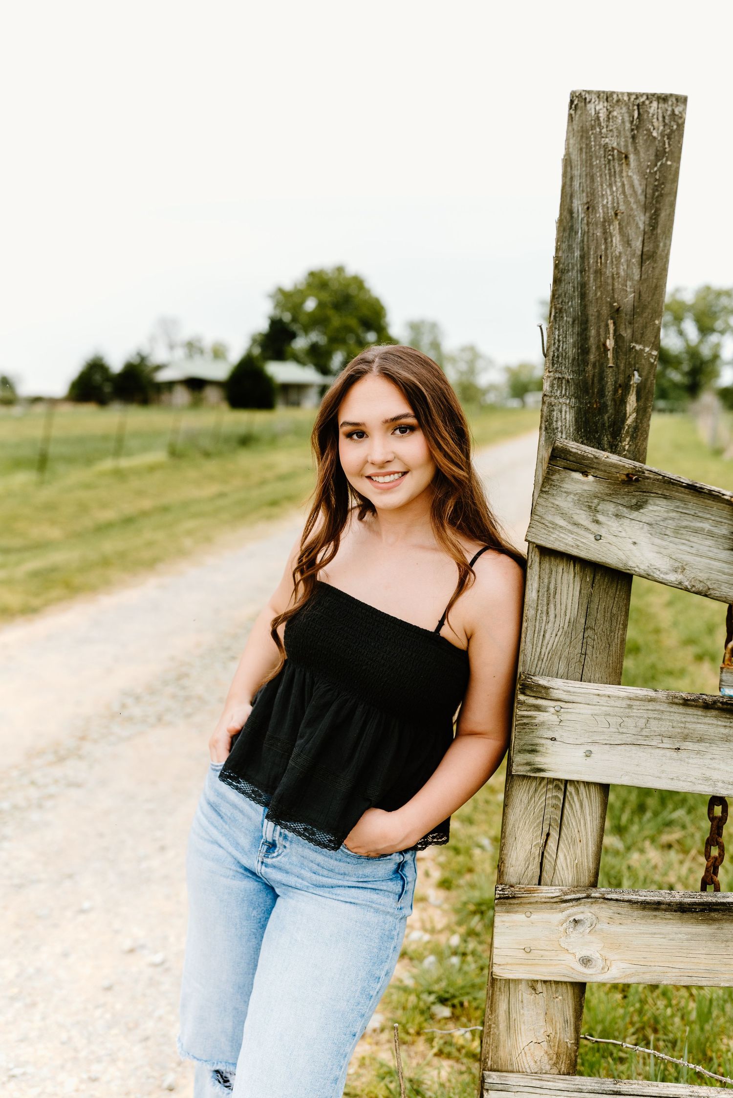 Outdoor portrait session by a rustic wooden fence on a country road.