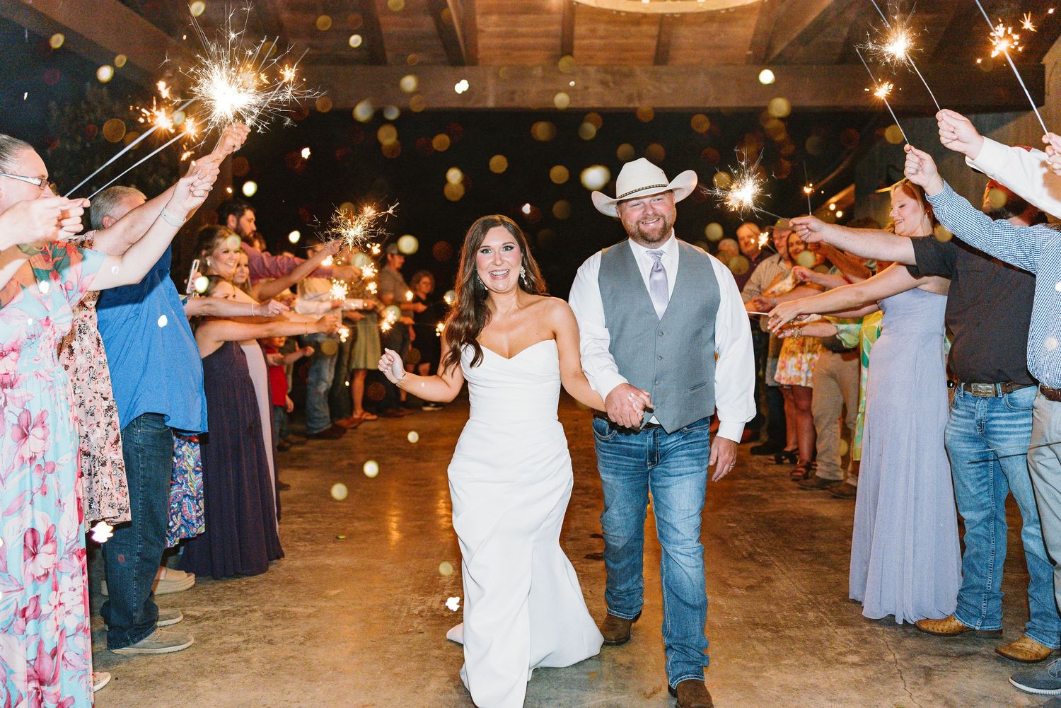 Wedding celebration exit with sparklers creating magical light trails in rustic barn venue.