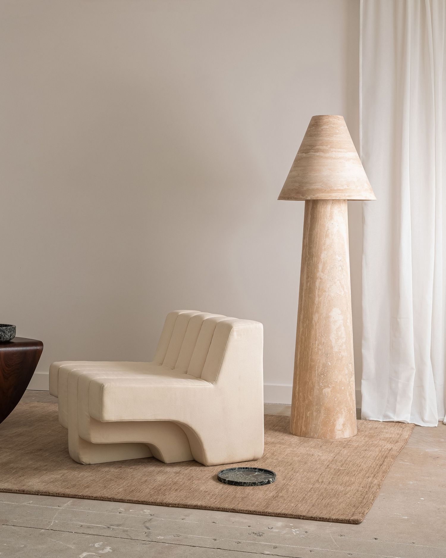 Minimalist interior scene featuring a curved cream-colored bench chair and tall wooden floor lamp on a natural jute rug.