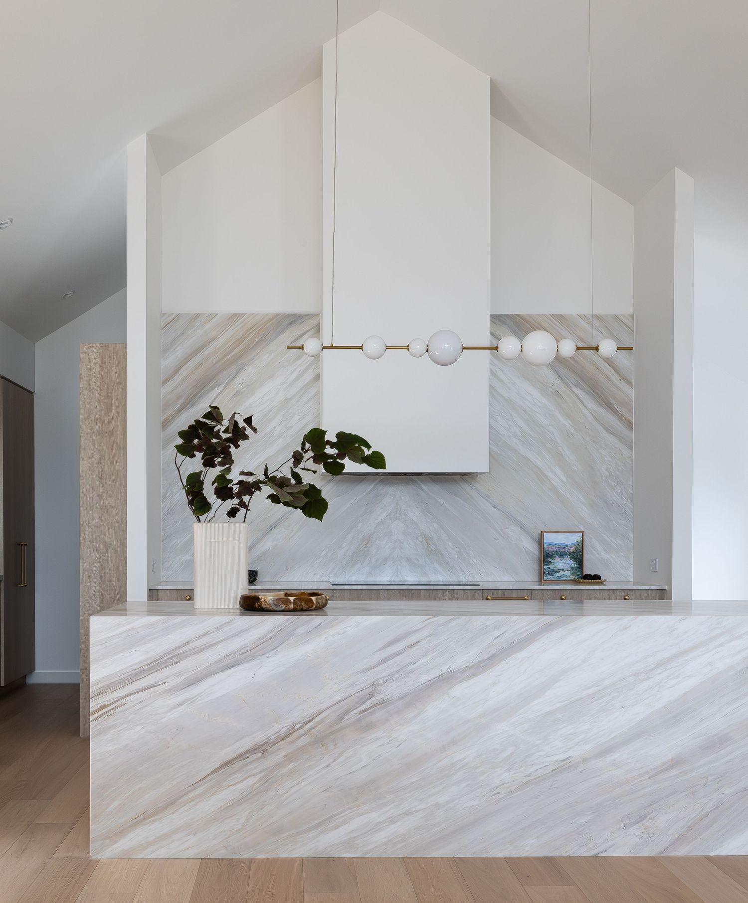 Modern white kitchen features sleek marble backsplash with dramatic gray veining and floating white cabinets.