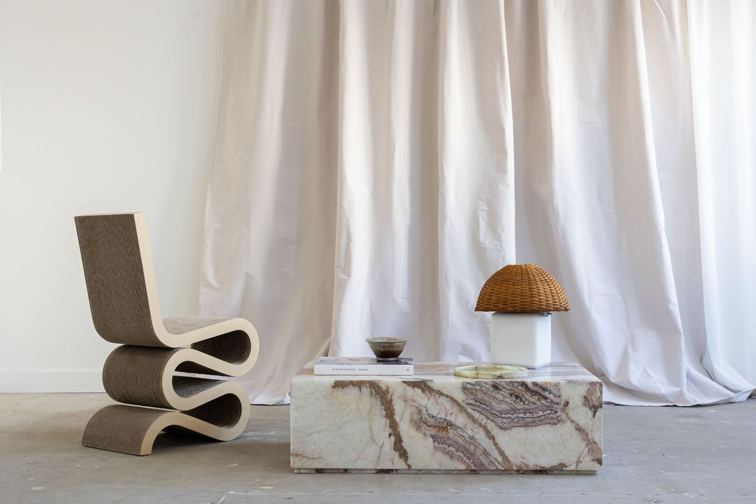White curtains and curved modern furniture create a soft, minimalist interior setting.
