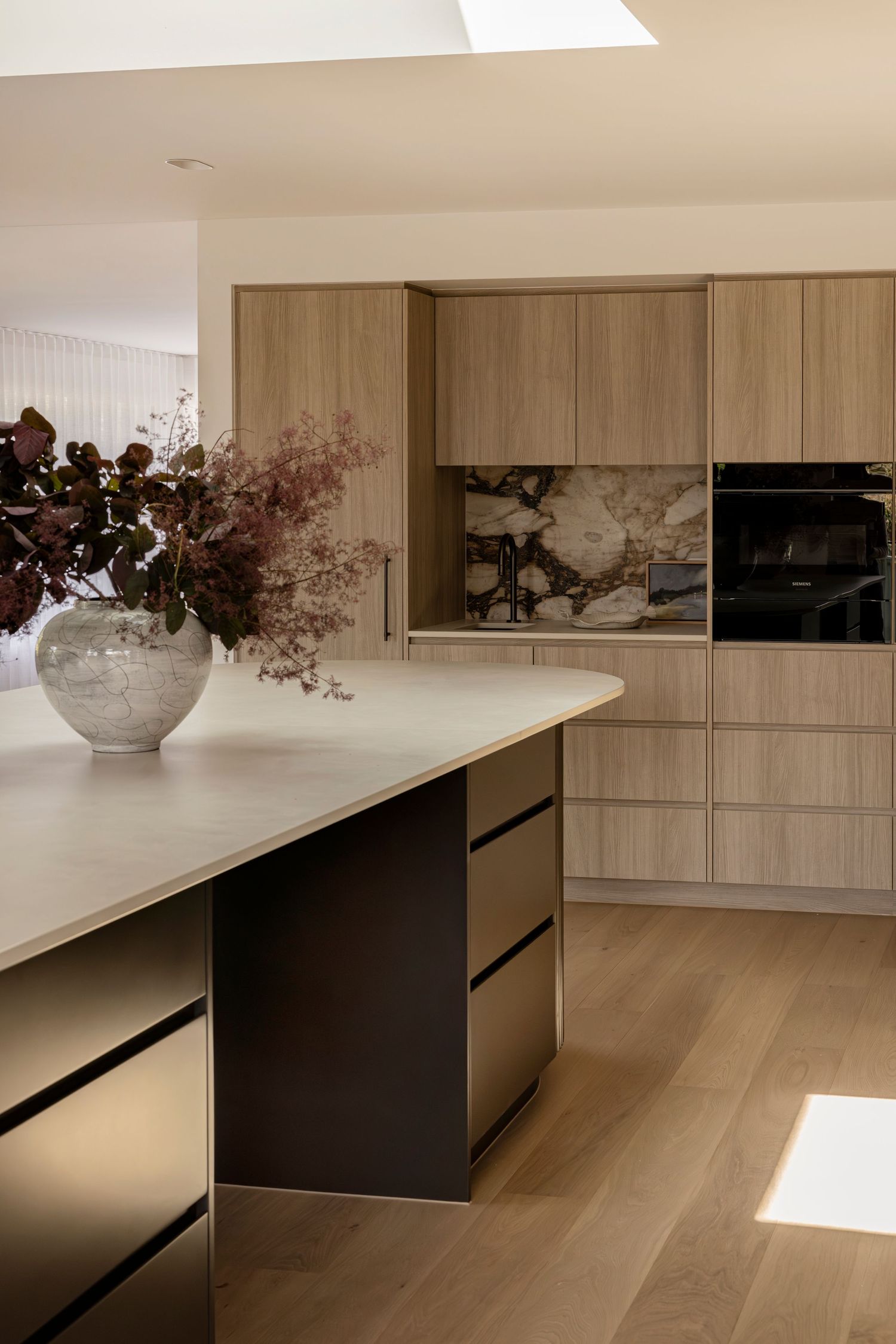 Modern kitchen design featuring light wood cabinets and a dark contrasting island. Canberra interior Photographer