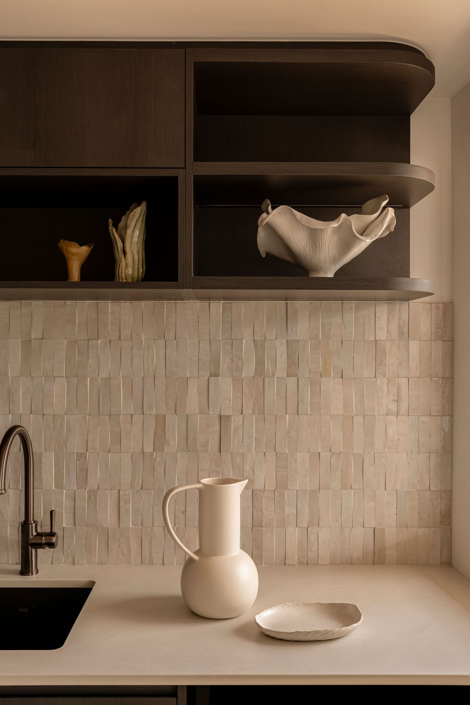 Minimalist kitchen shelving with white ceramic pitchers and textured tile backsplash in warm neutral tones. Canberra interior Photographer