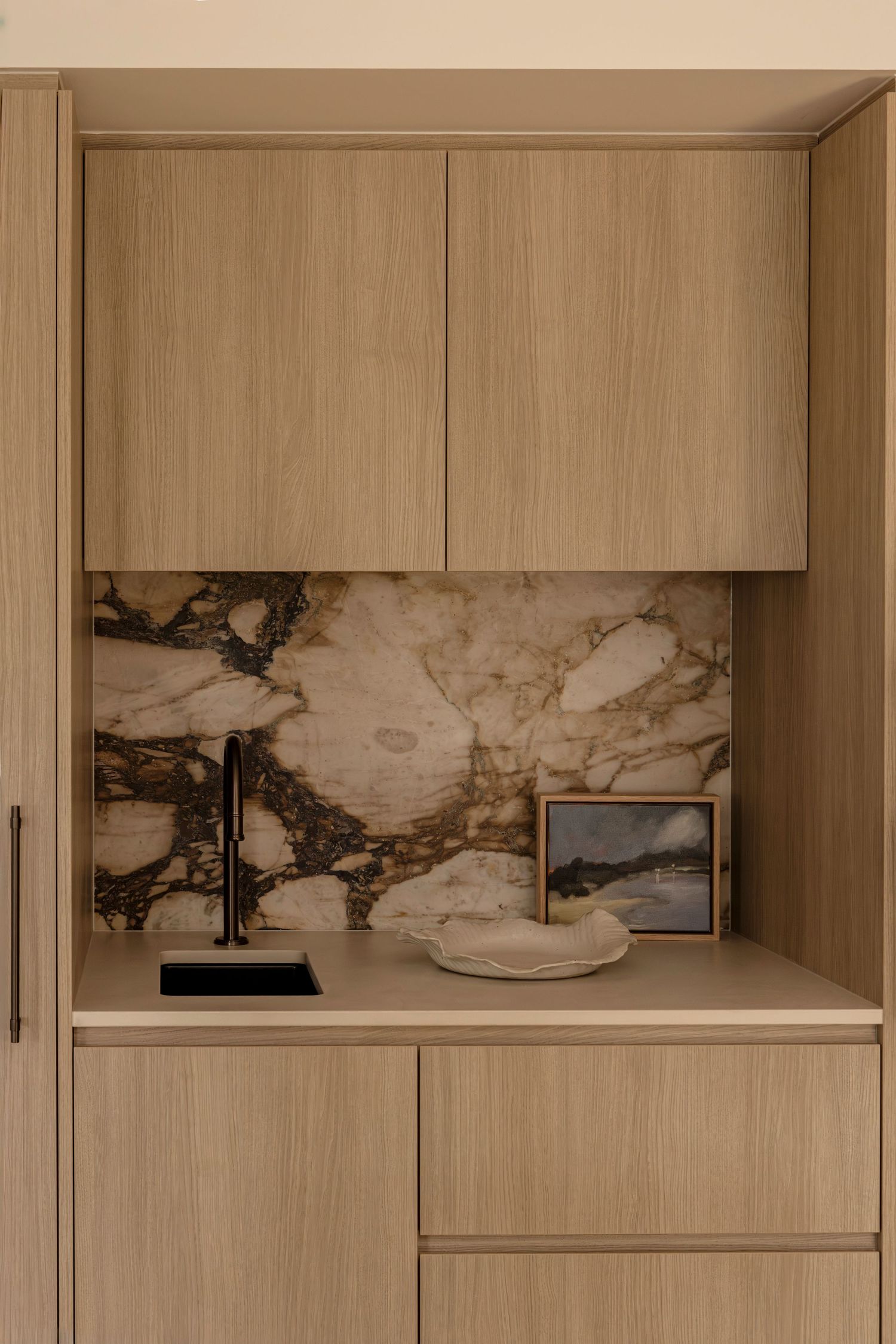 Modern built-in cabinet with light wood finish and marble backsplash featuring minimalist decor and black table lamp. Canberra interior Phot
