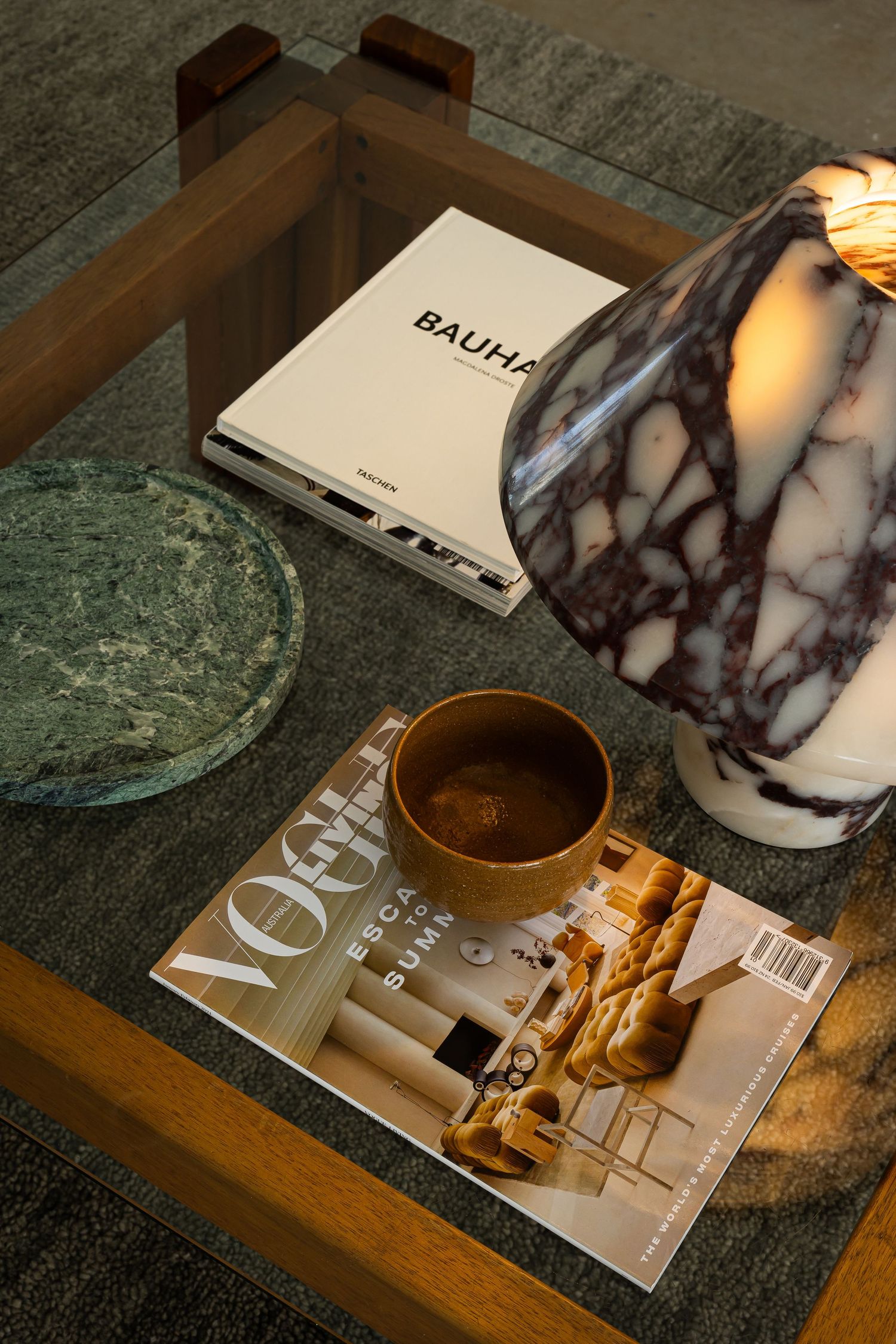 Lifestyle magazines and decorative marble items arranged on green textured surface with warm lighting.