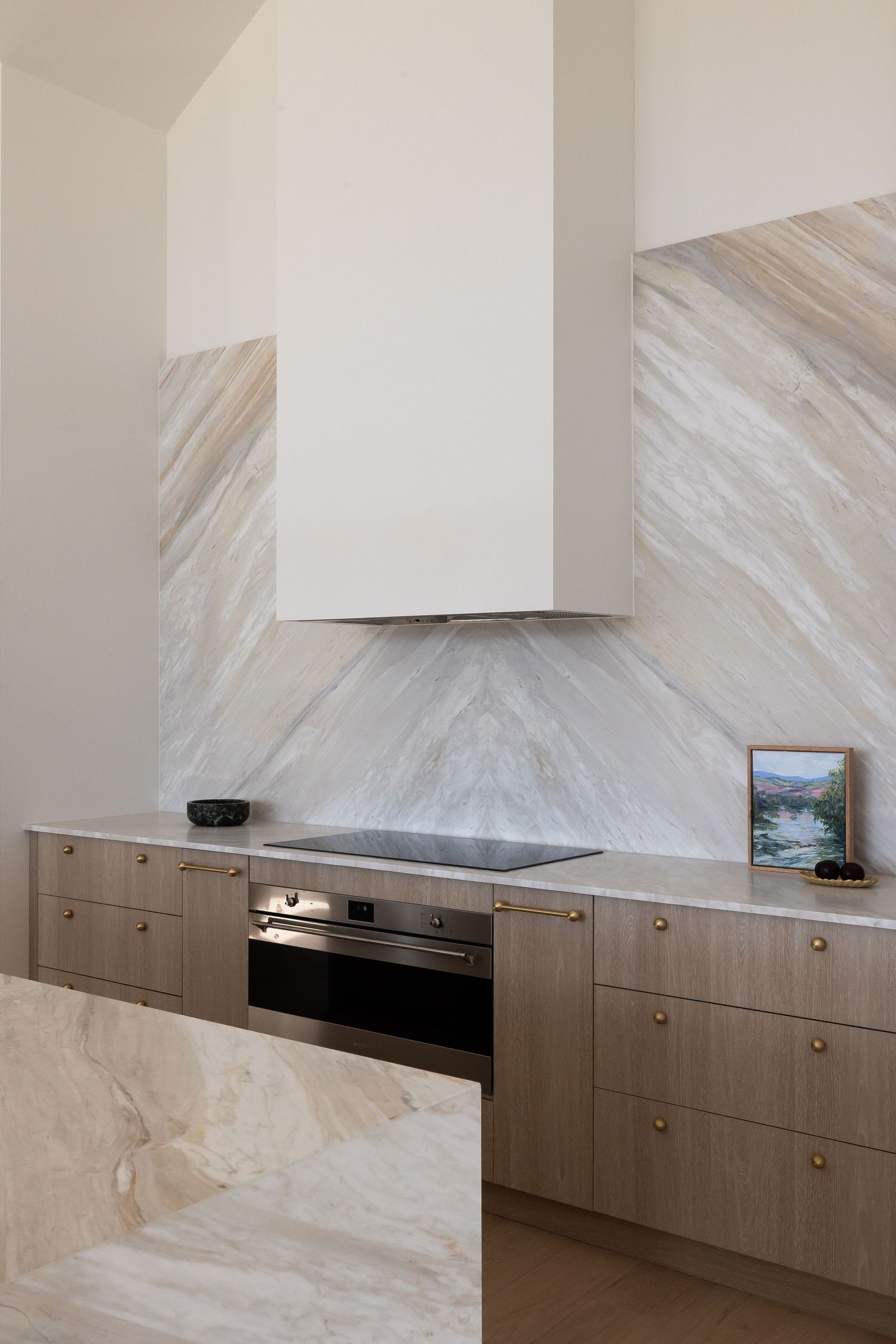 Sleek kitchen design with marble backsplash and light wood cabinetry featuring built-in appliances.