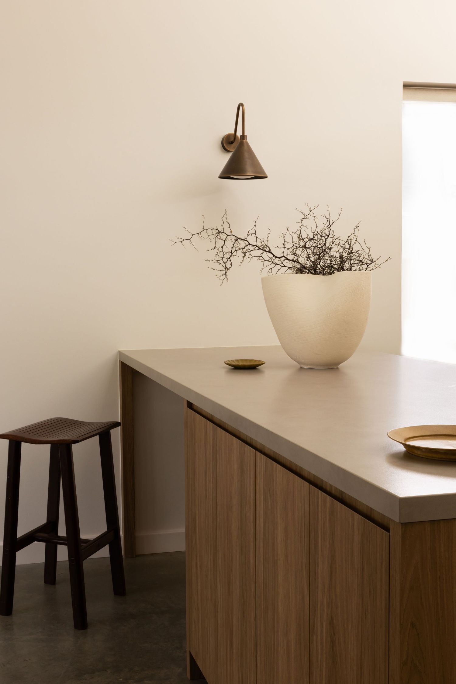 Minimalist interior design featuring wooden furniture, white ceramic vases, and subtle lighting against neutral walls.