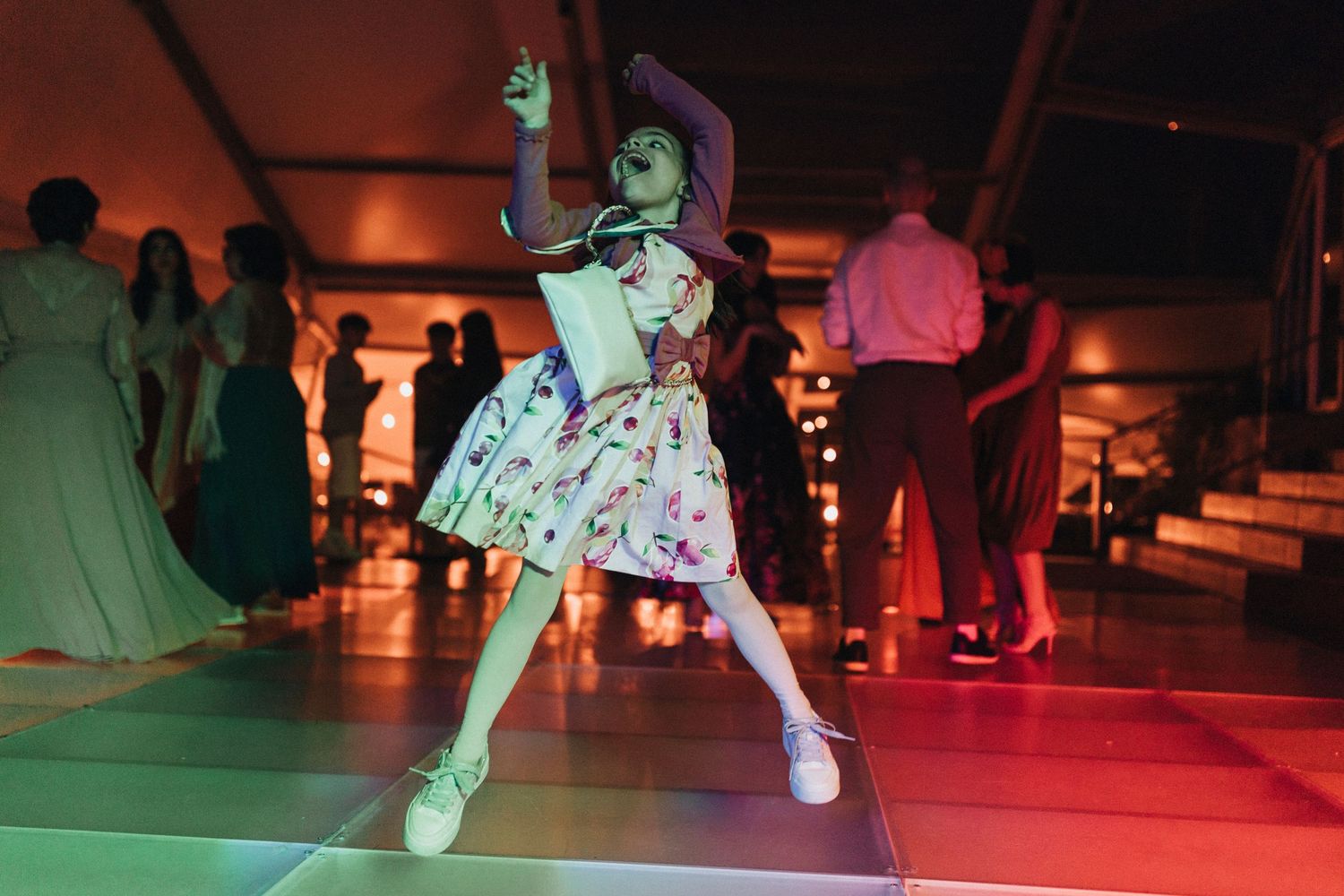 Dancers move energetically under colorful lighting at a nighttime party or event.