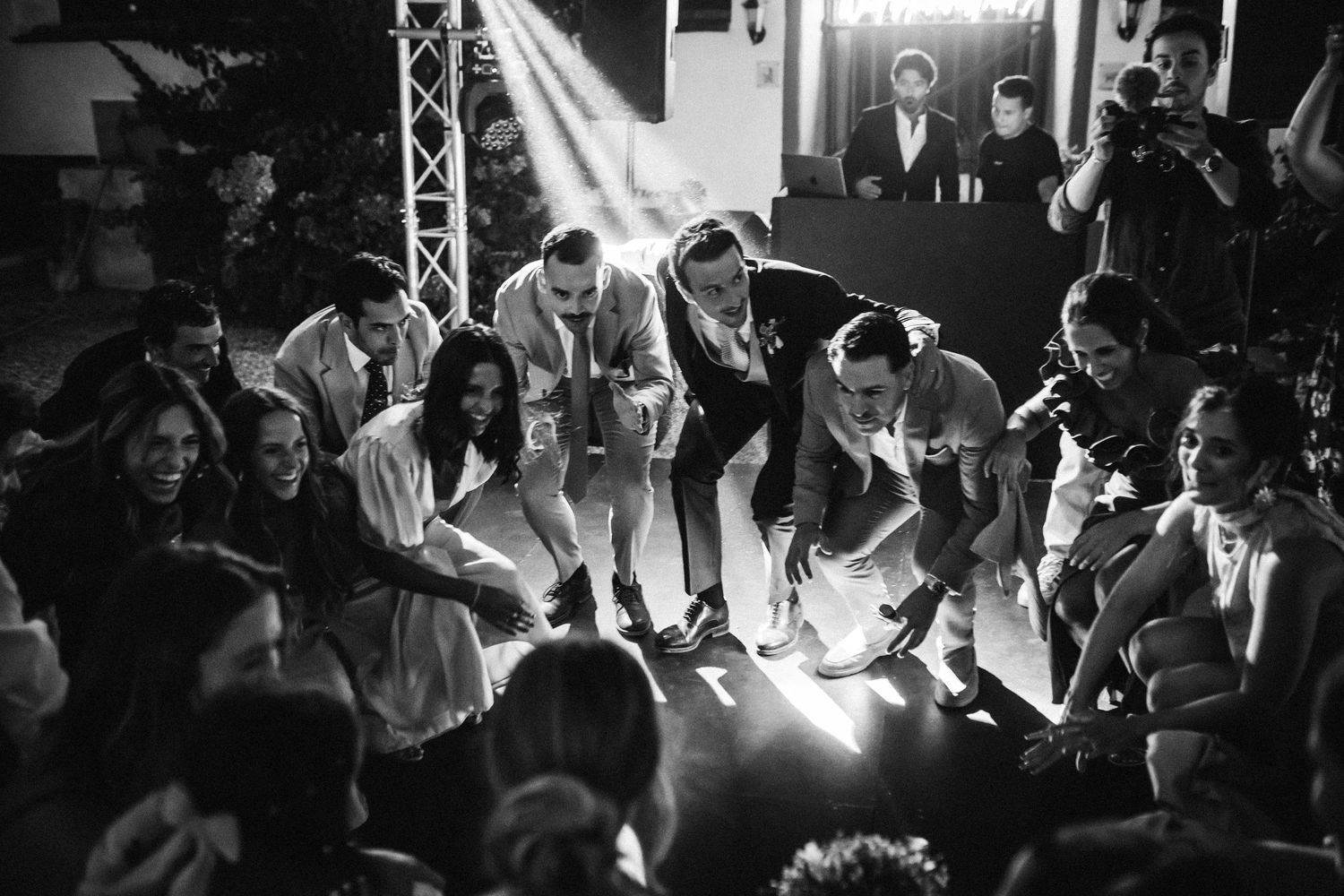 Energetic dance floor scene at a wedding reception with dramatic lighting and silhouettes.