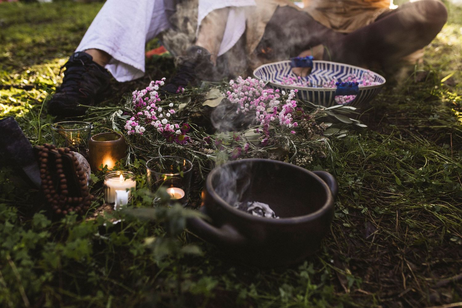 Atmospheric outdoor table setting with glowing candles and purple flowers in a moody garden setting.