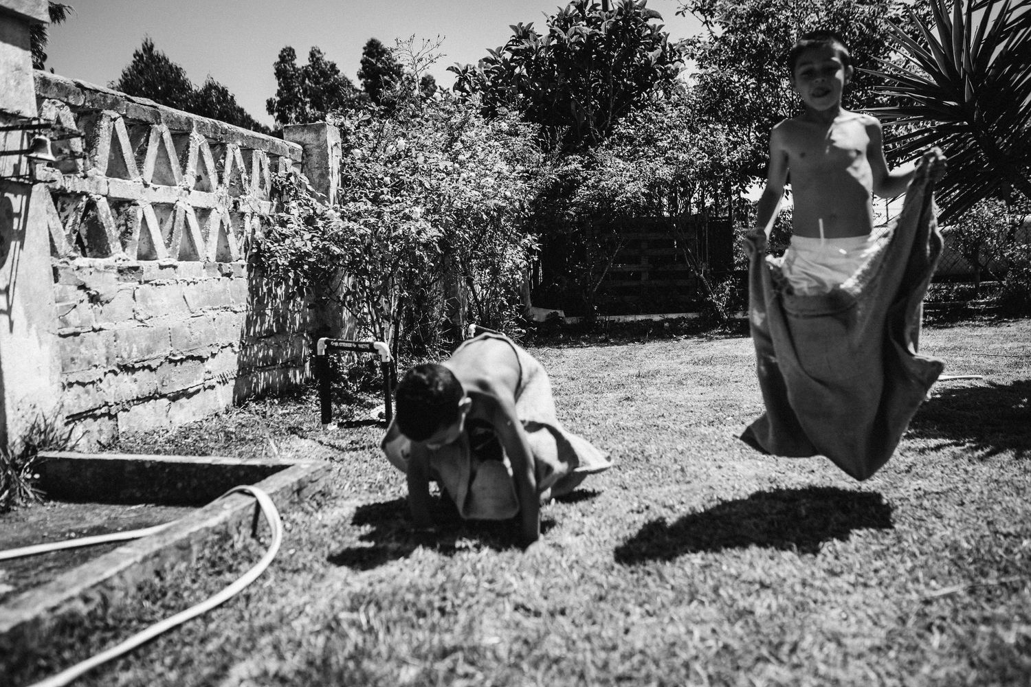 Black and white sequence of people playing and relaxing in an outdoor garden setting.