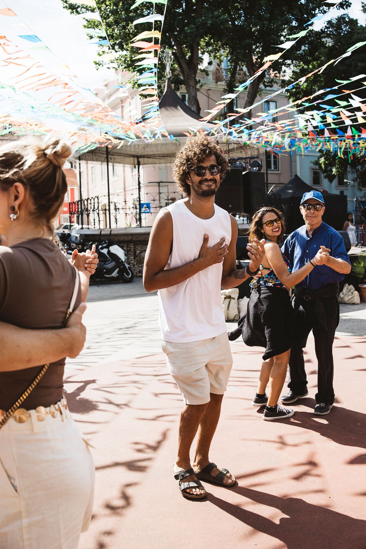 Candid shots of people dancing and celebrating outdoors under colorful party decorations on a sunny day.