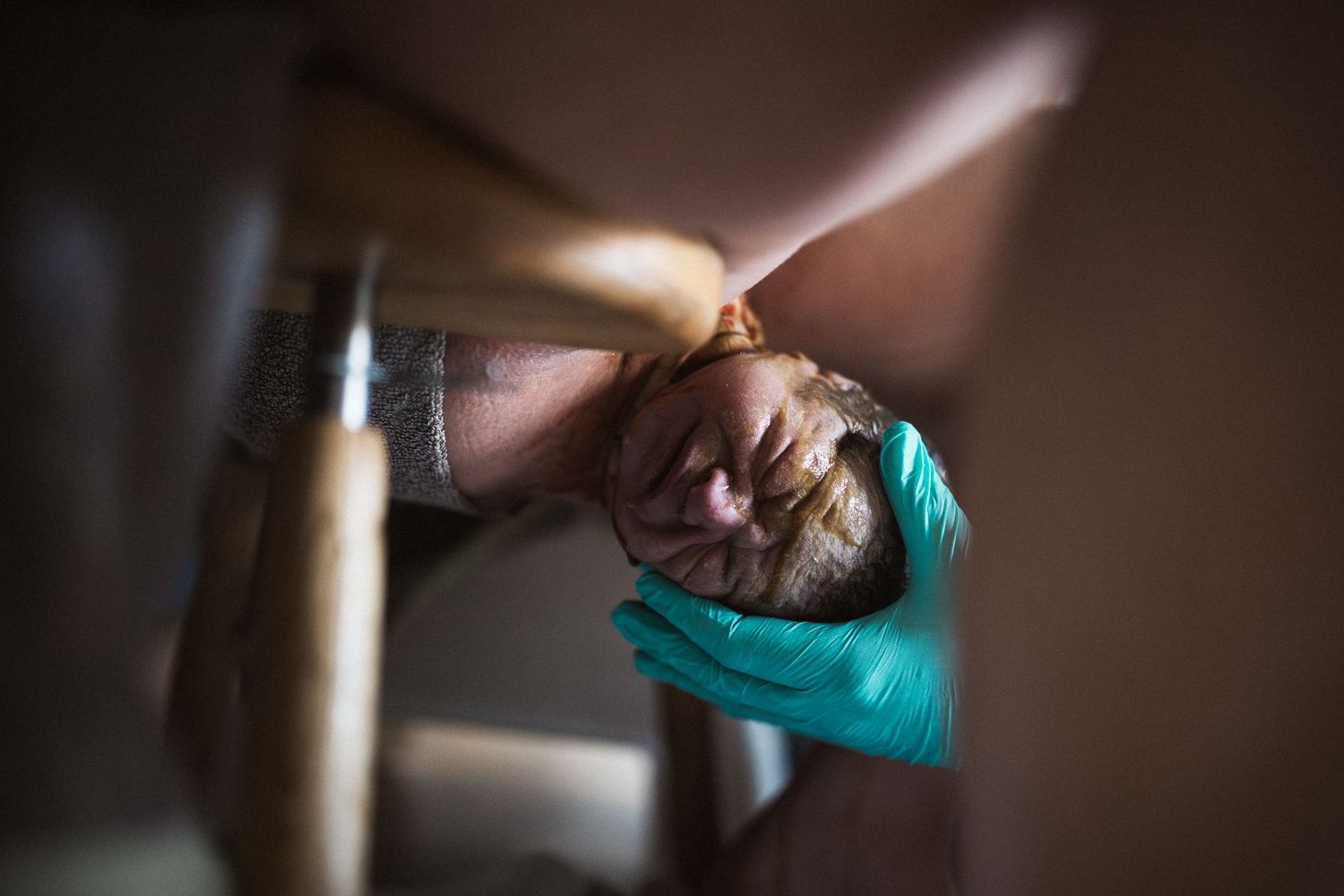 Close-up artistic photo of childbirth through medical equipment in teal tones.