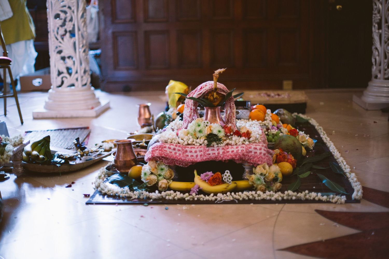 Colorful fruit and floral arrangements displayed on ornate platters at an elegant indoor event.