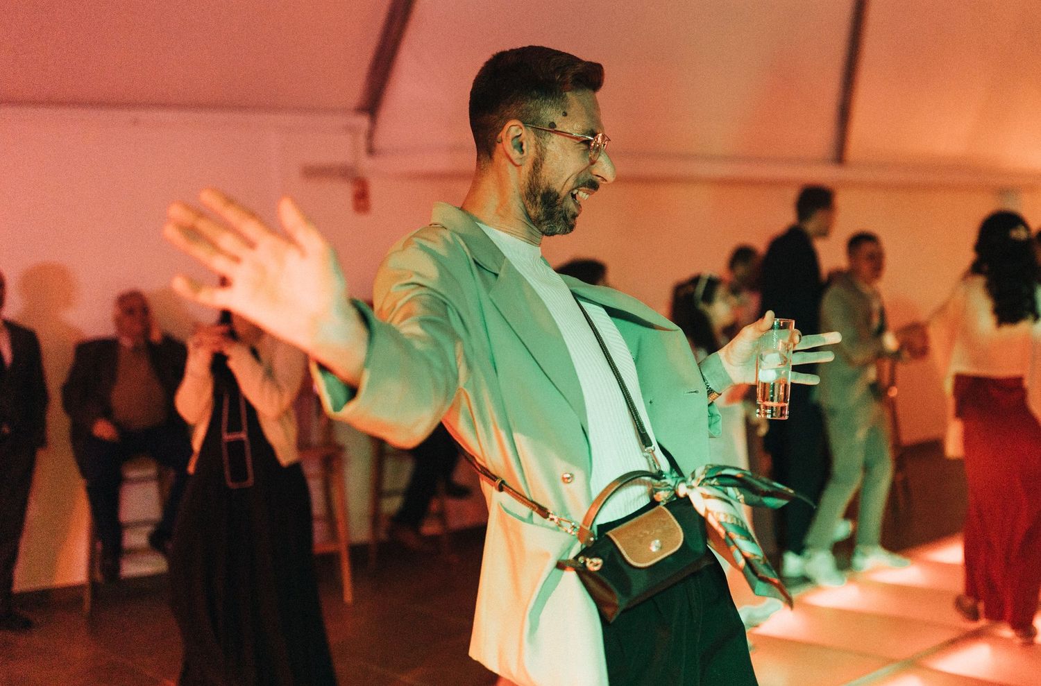 Couples dancing together at a wedding reception with colorful pink and blue lighting effects.