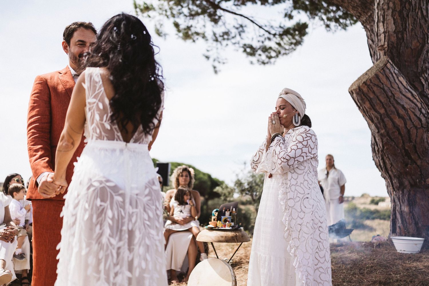 Outdoor wedding ceremony setup with white chairs and natural decor under pine trees.