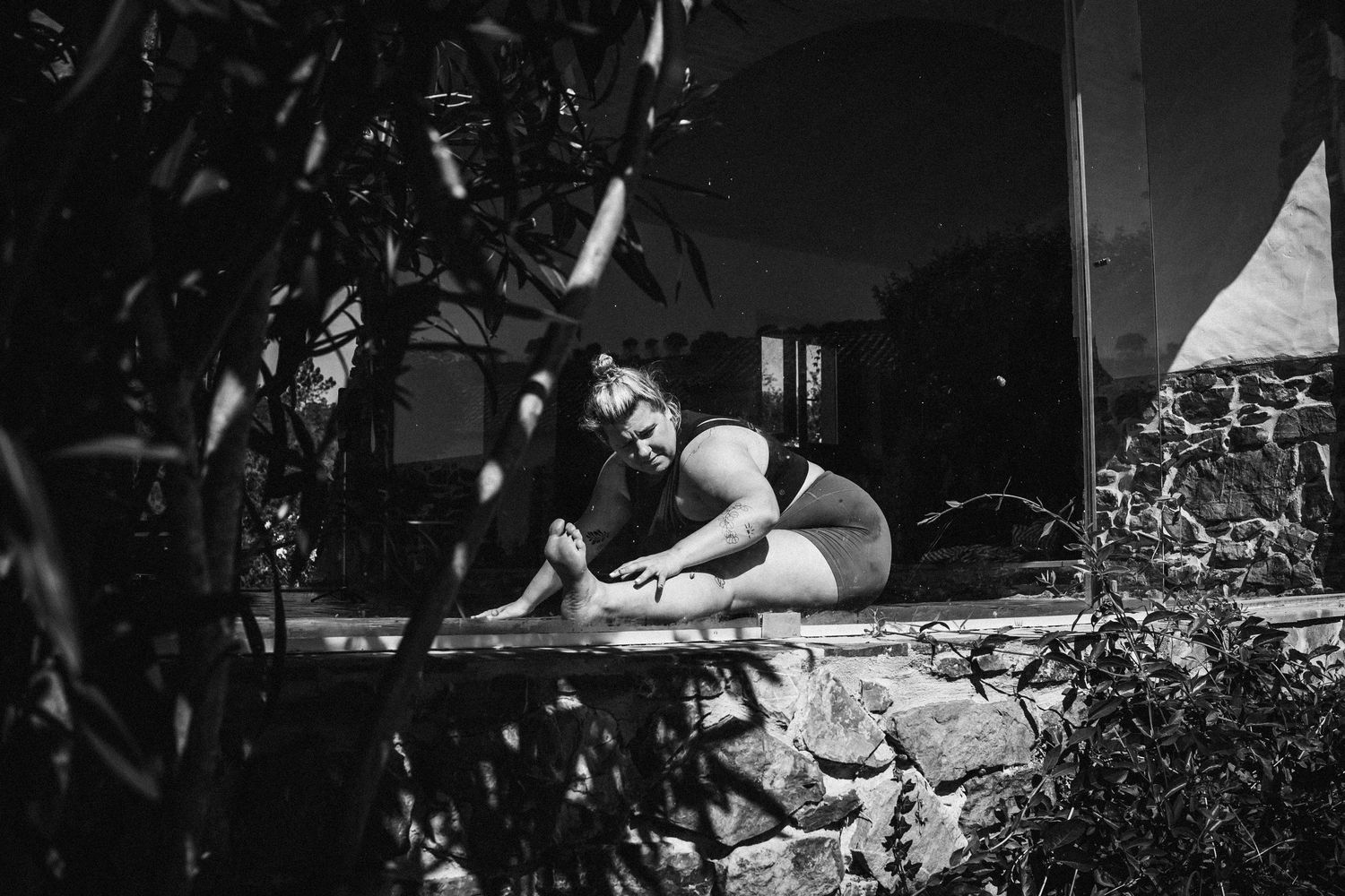 Black and white photo showing a person lounging outdoors on a patio chair in a relaxed summer setting.
