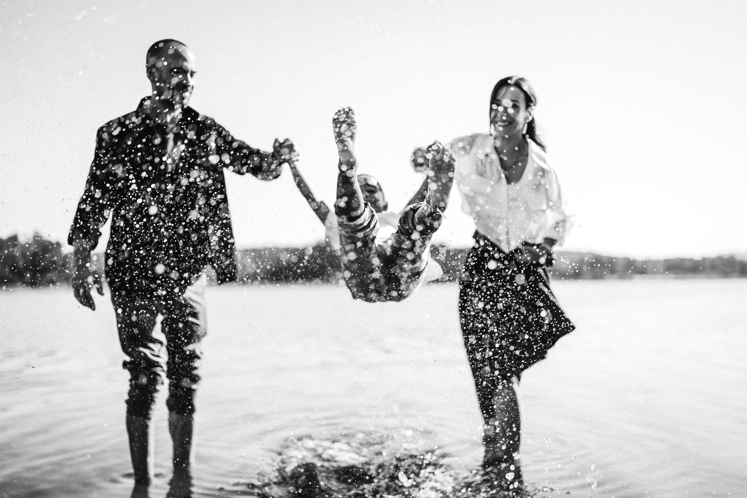 A black and white collage of people playing and splashing in water on a sunny summer day.
