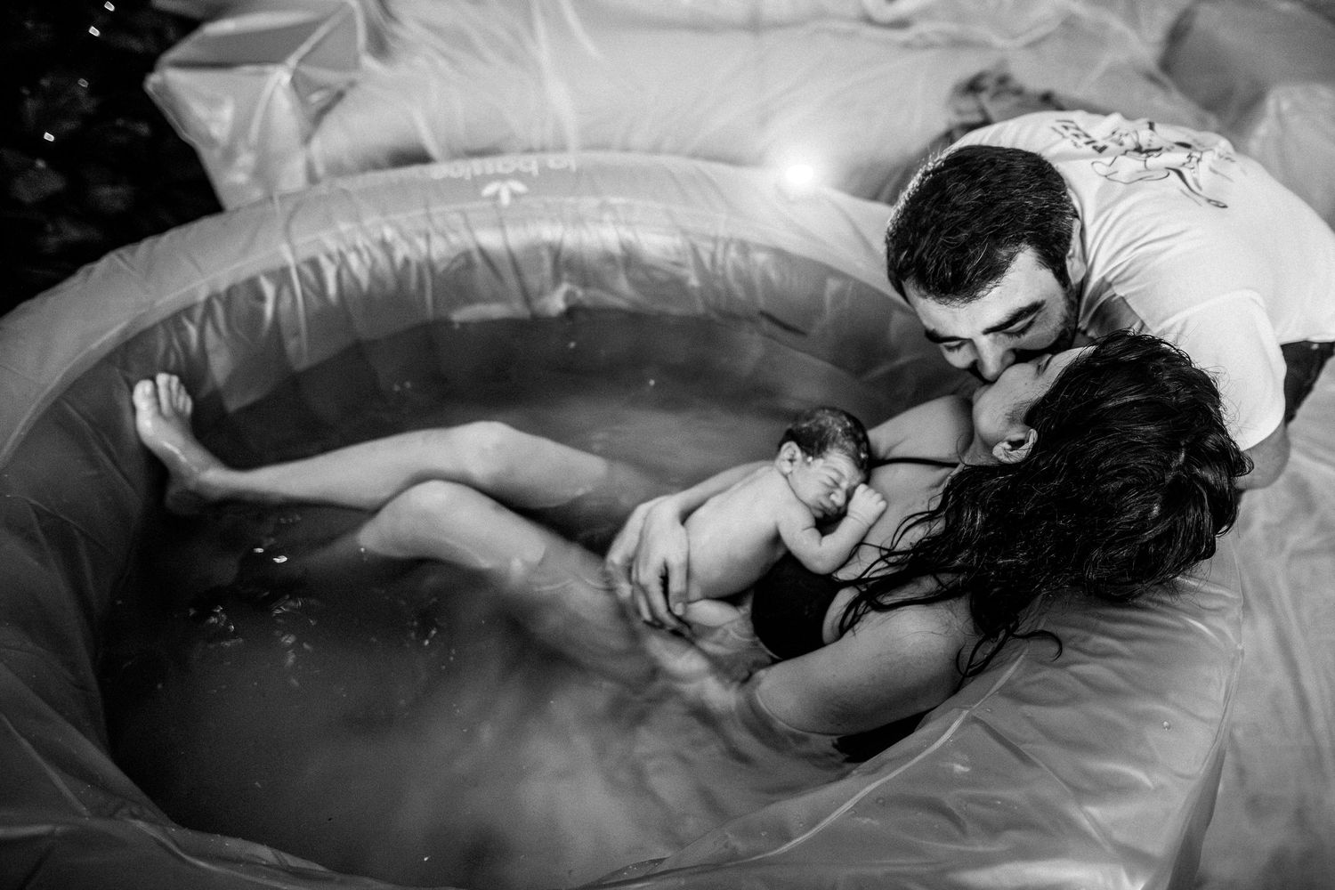 Candid black and white photography documenting a powerful water birth moment.