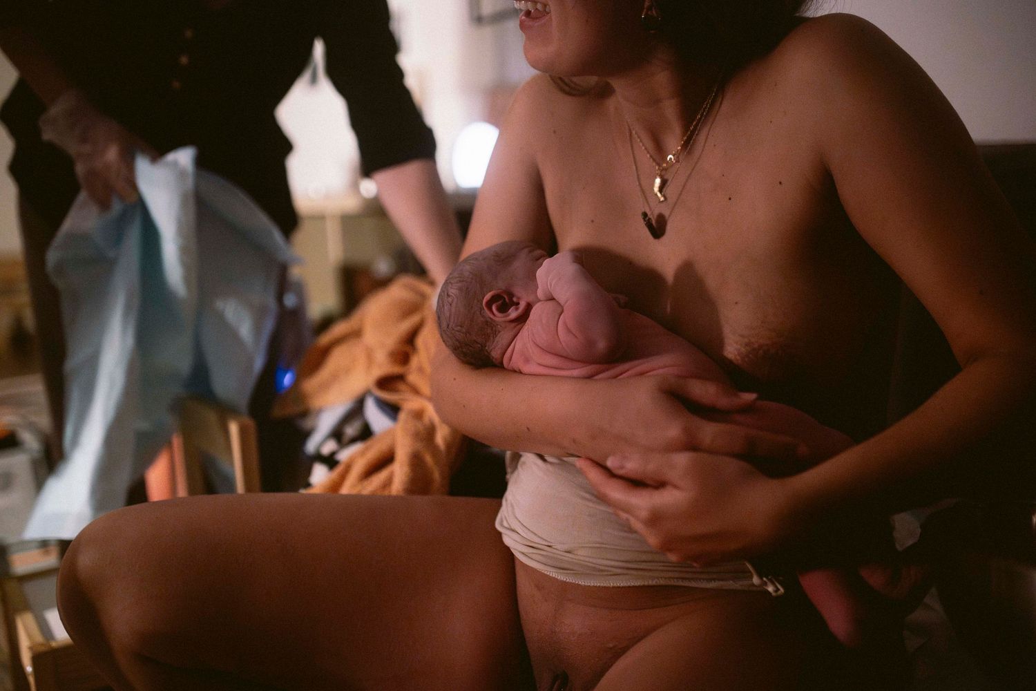 A tender moment during childbirth captured in moody lighting and intimate close-up photography.