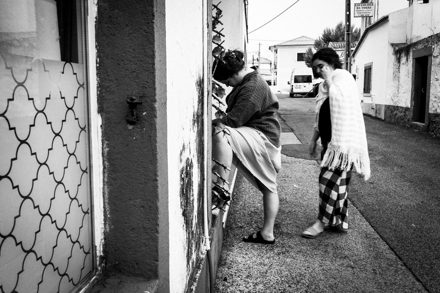 Black and white street photography shows figures walking through narrow alleyways and doorways in an urban setting.