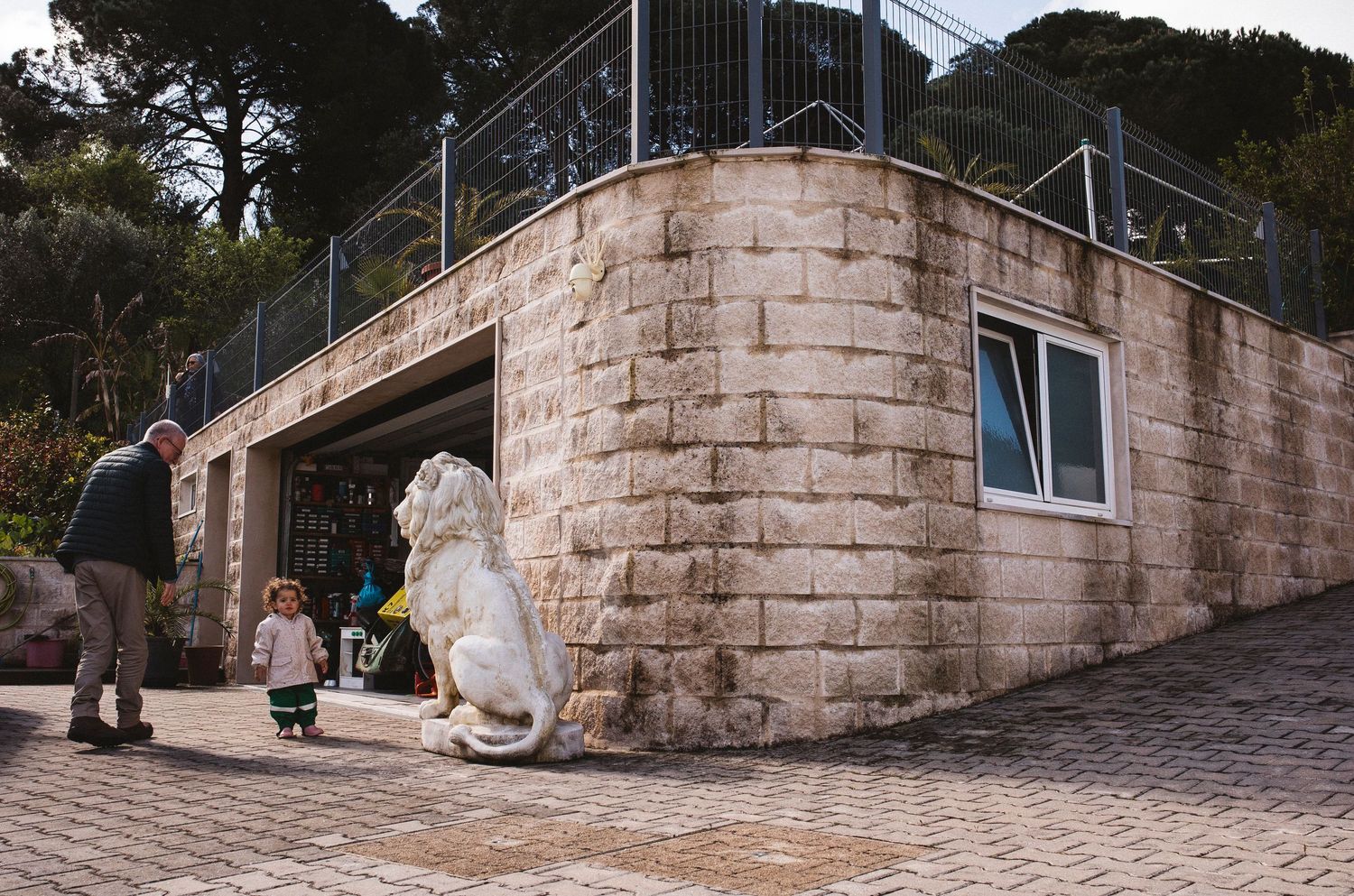 A curved stone wall with metal handrails leads up a steep staircase in an urban setting.
