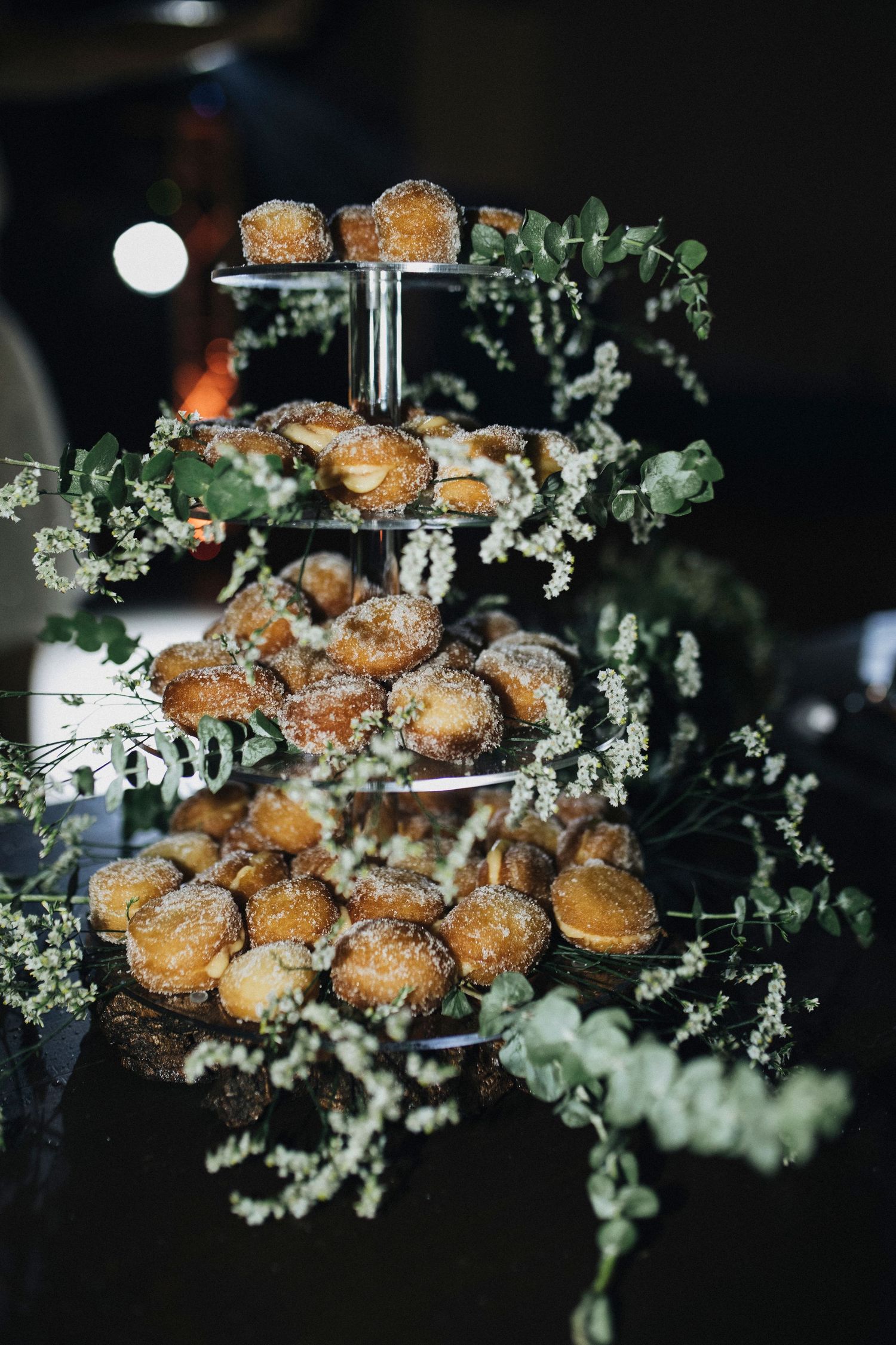 Freshly baked cream puffs dusted with powdered sugar arranged on a dark surface with delicate white flowers.