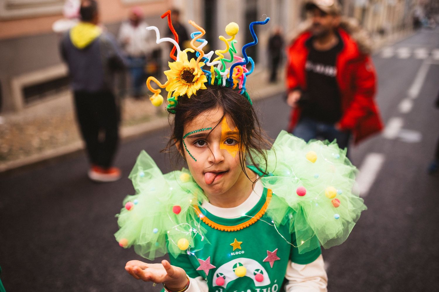 Children in green costumes and colorful decorations participate in a street parade or festival.