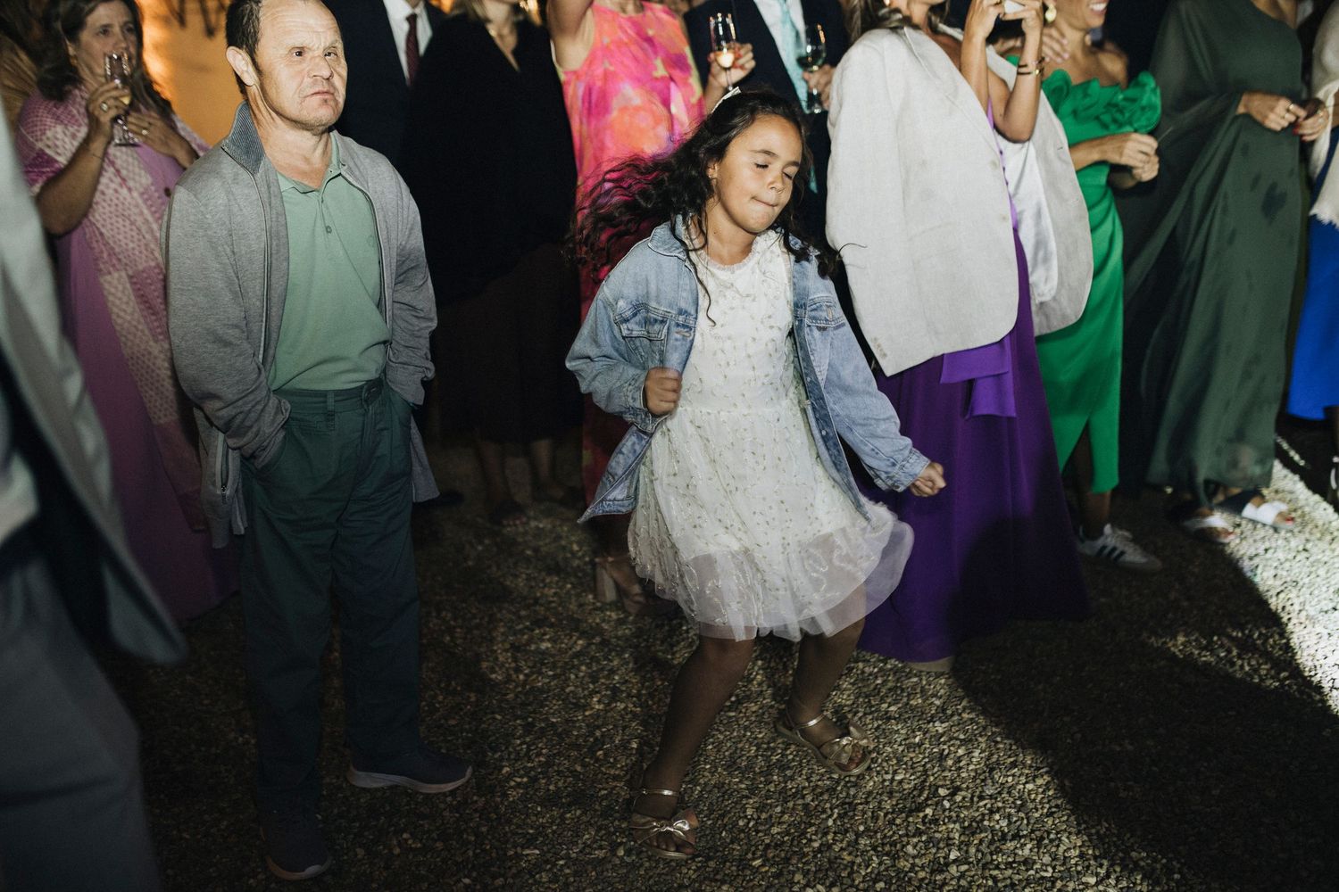 Wedding reception dance floor filled with guests celebrating in evening lighting.