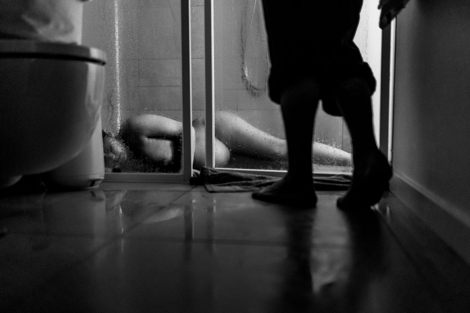 Silhouetted figures cast dramatic shadows on a bright floor beneath a doorway.
