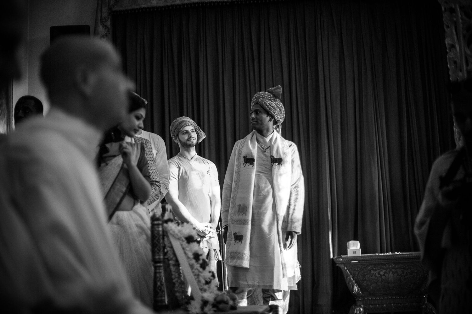 Black and white photo of performers on stage with dramatic curtain backdrop during theatrical performance.