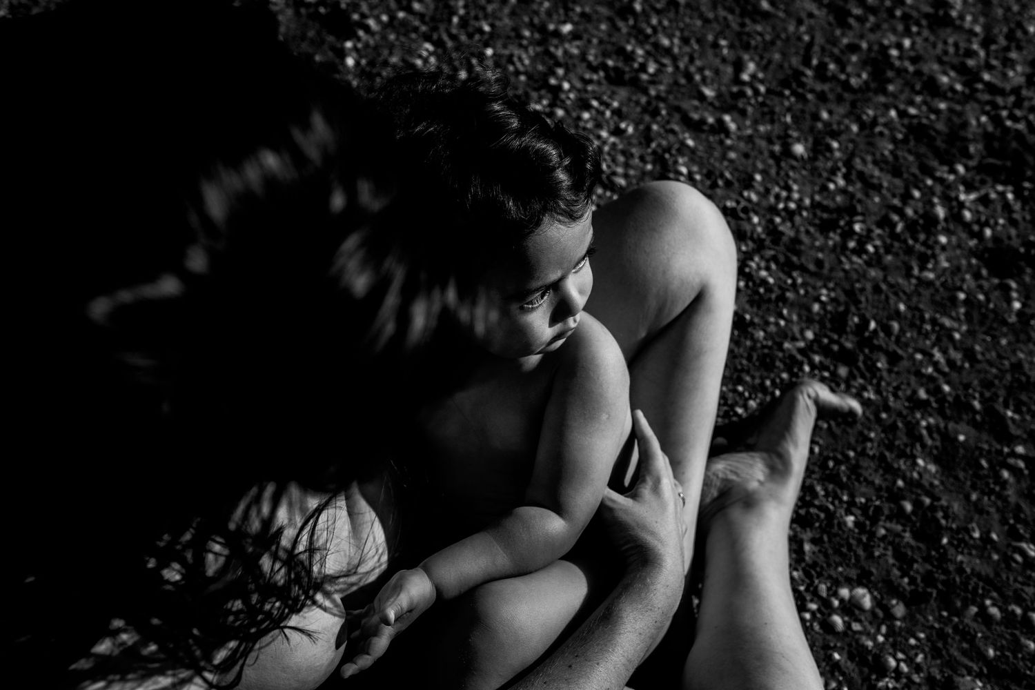 A series of intimate black and white photographs showing tender moments between two people on a dark textured surface.
